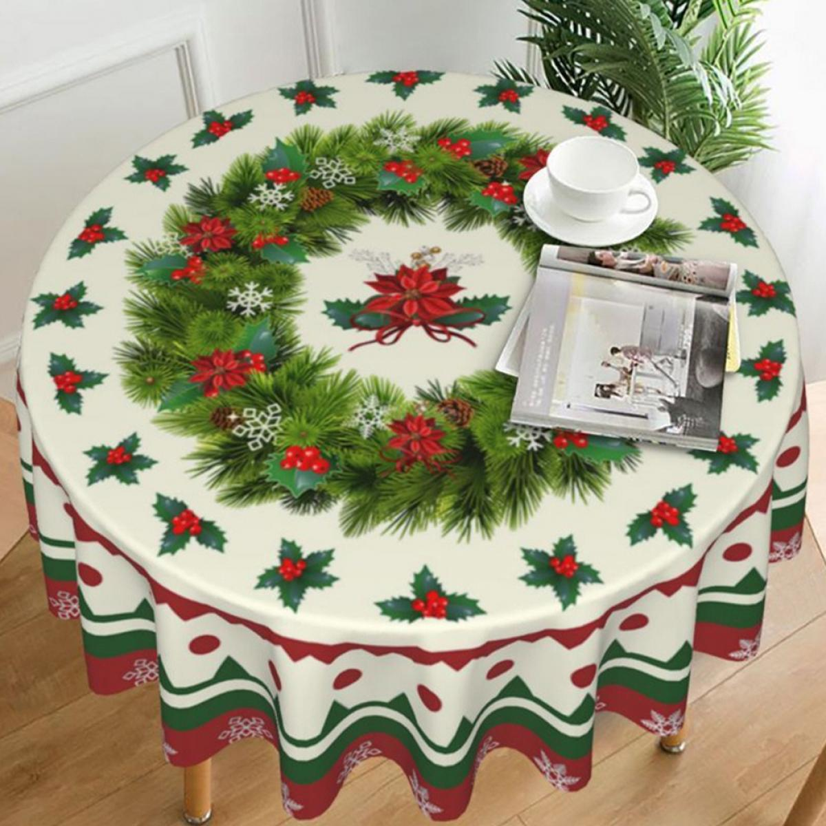 Ein runder Tisch mit einer Weihnachtstischdecke. Die Tischdecke zeigt einen Kranz, rote Blumen und Schneeflocken. Eine Tasse und eine Zeitschrift liegen darauf.