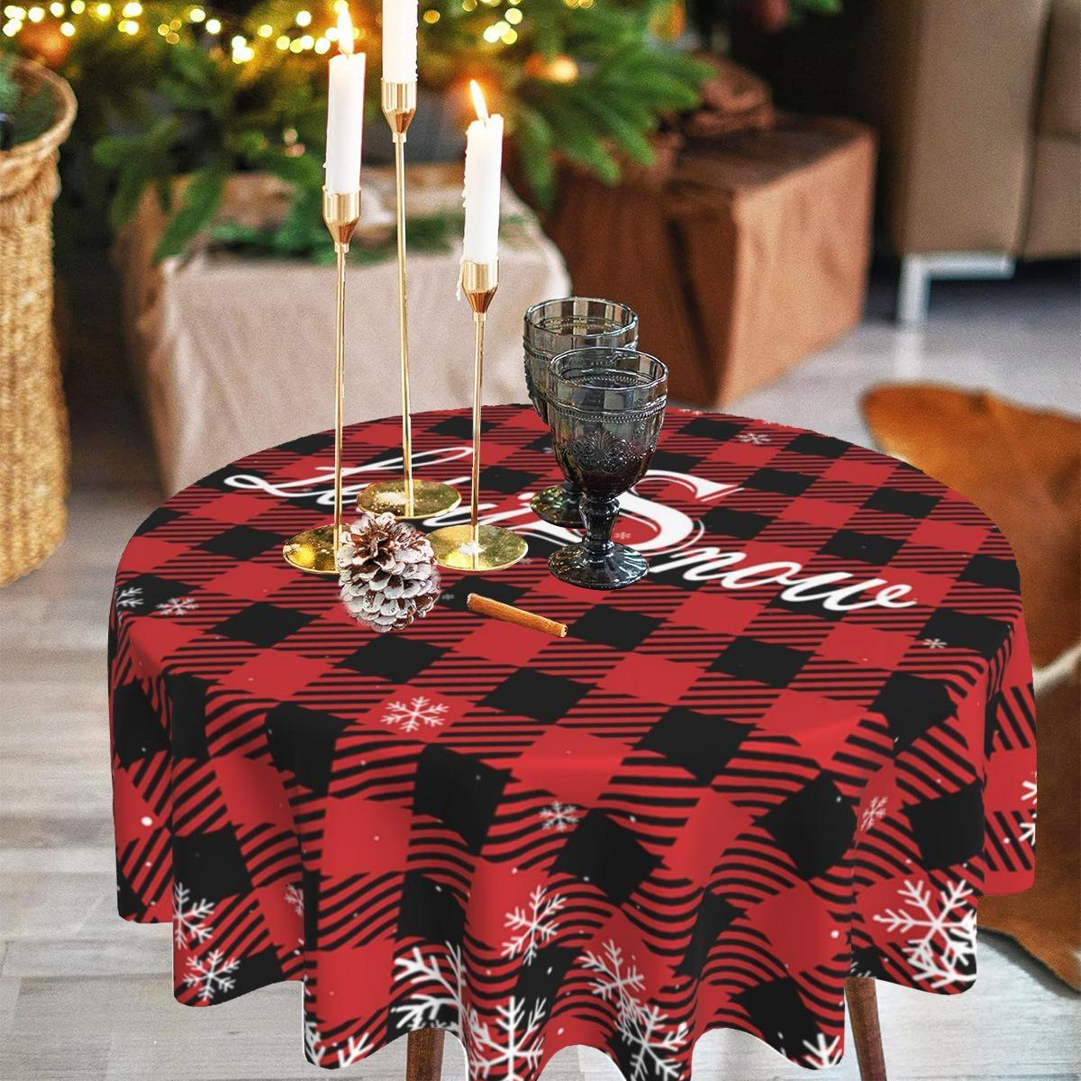 Ein runder Tisch mit rot-schwarz karierter Tischdecke. Kerzen, Gläser und ein Tannenzapfen stehen auf dem Tisch. Weihnachtsdeko im Hintergrund.