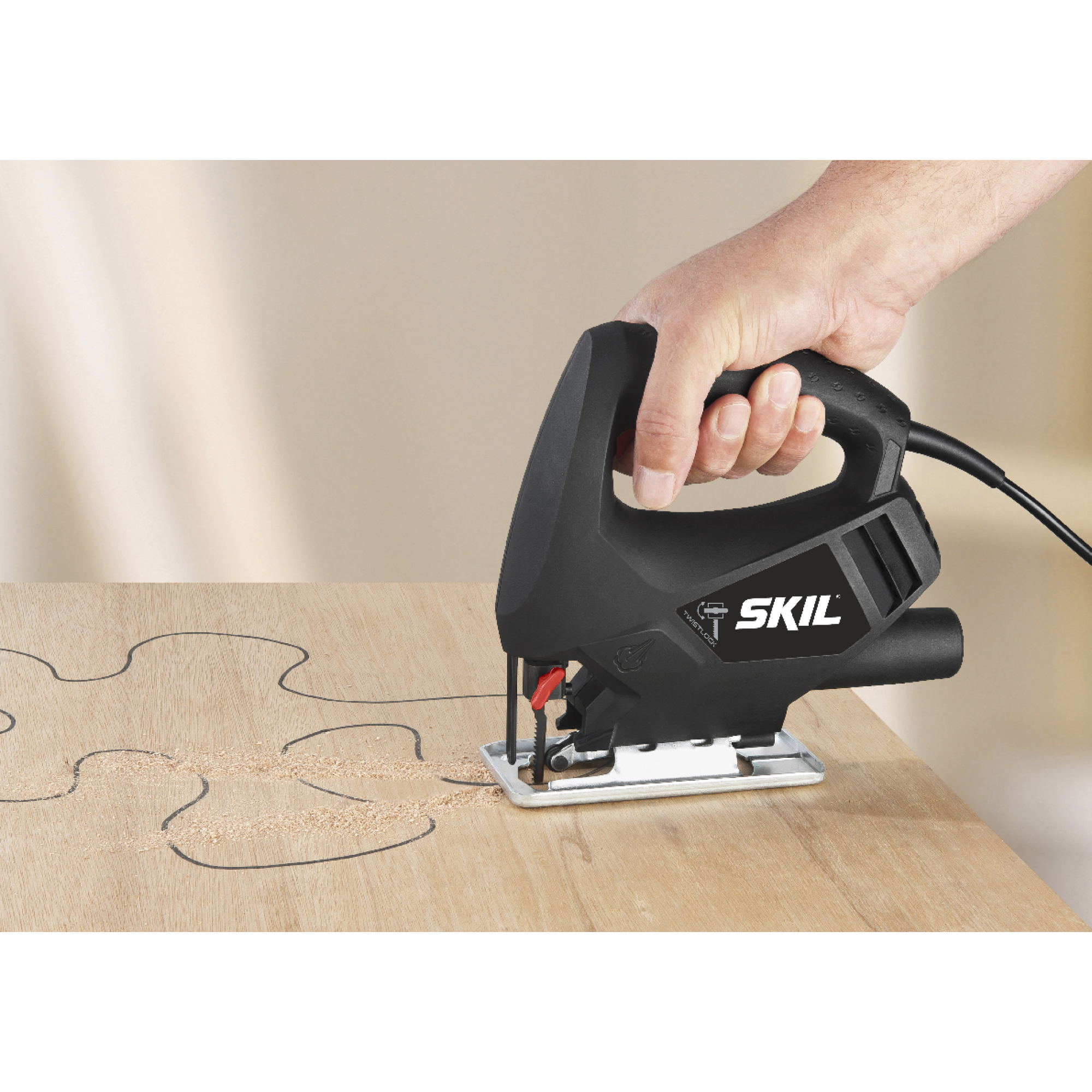 Een decoupeerzaag wordt door een hand vastgehouden en snijdt een houten plank. De plank heeft een getekende puzzelvorm. De achtergrond is vaag.