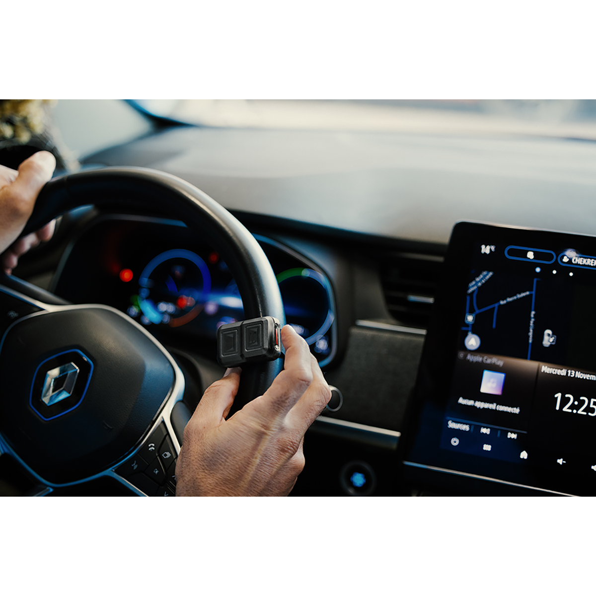 Hände am Lenkrad, halten ein kleines Gerät. Digitalanzeige auf dem Armaturenbrett mit Uhrzeit und Navigation.