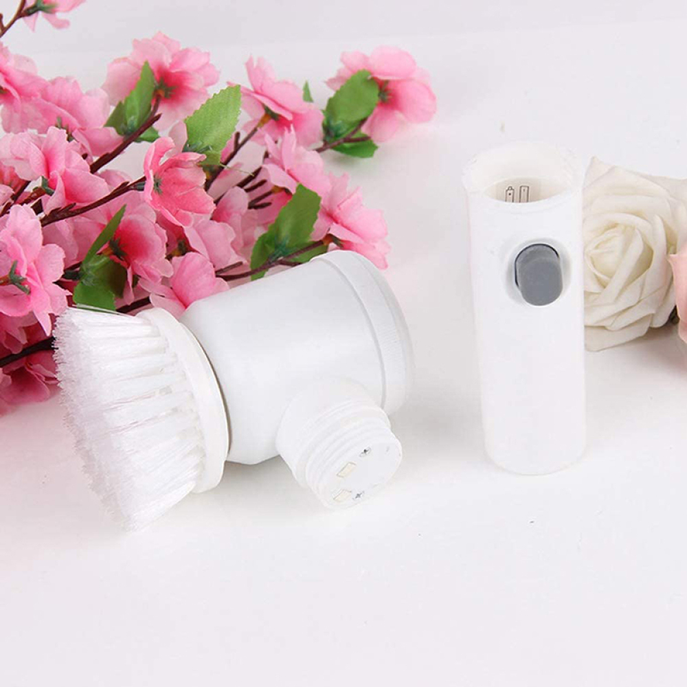 Weiße Reinigungsbürste und abnehmbarer Griff mit grauem Knopf, rosa Blumen im Hintergrund. Die Bürste ist im linken Vordergrund.
