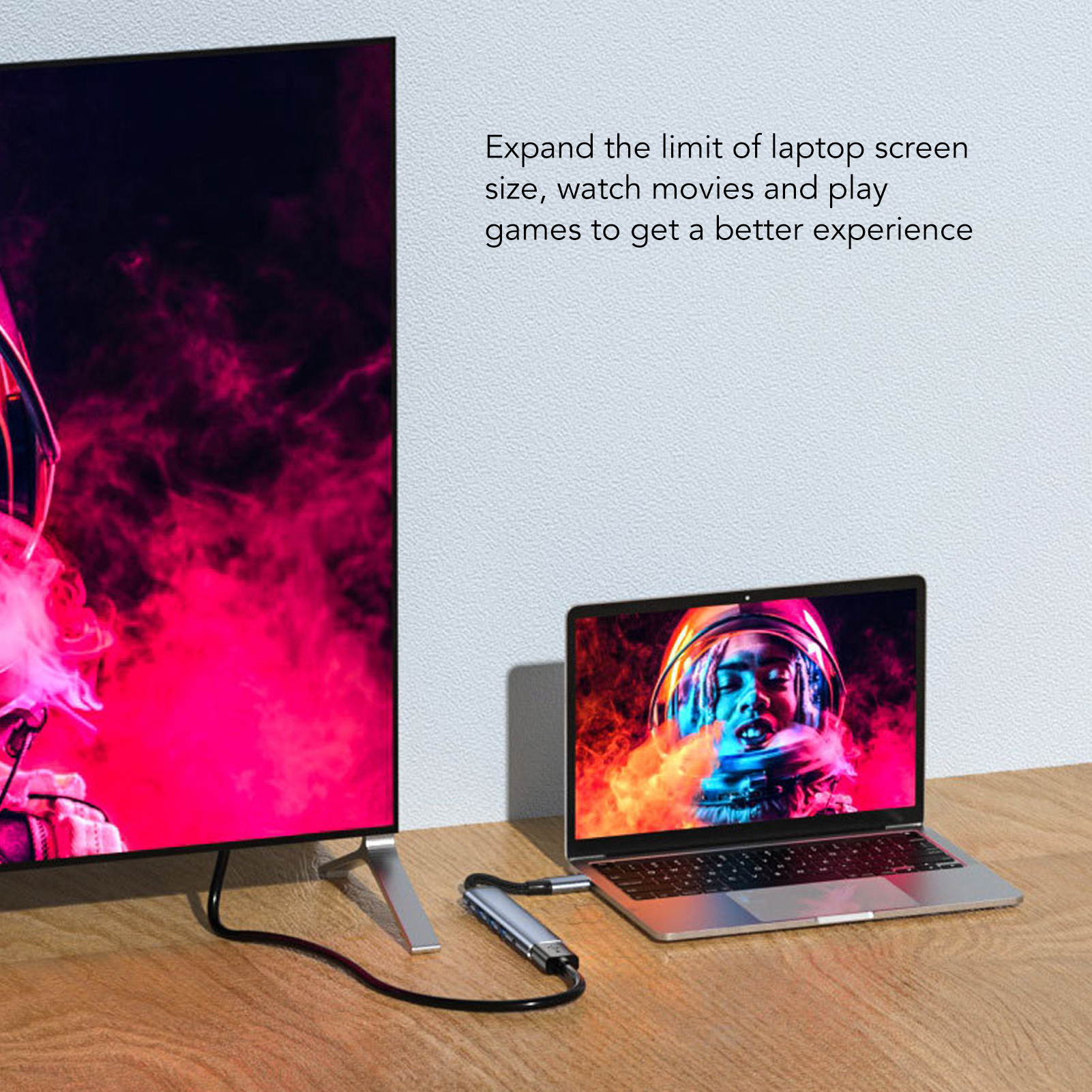 Laptop mit Fernseher verbunden. Der Laptop zeigt ein Astronautenbild. Ein Kabel verbindet die Geräte auf Holz.