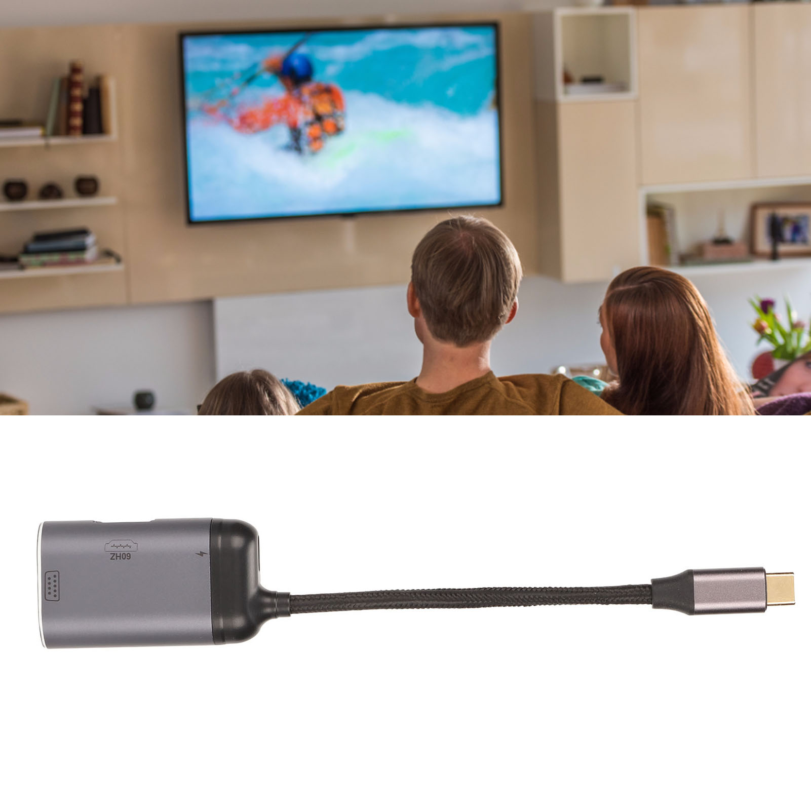 Eine Familie schaut fern. Ein grauer Adapter mit schwarzem Kabel im Vordergrund. Der Fernseher zeigt einen Snowboarder.