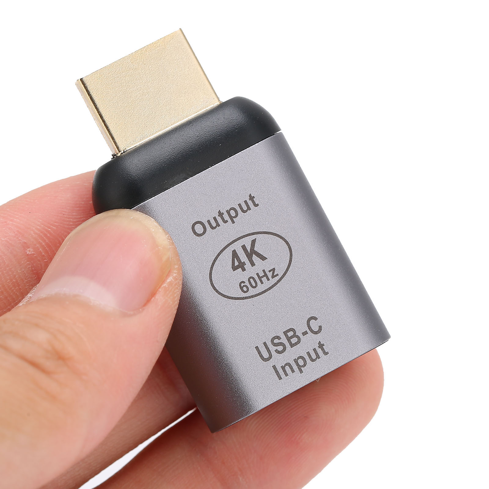 Ein silberner USB-C-zu-HDMI-Adapter wird von einer Hand gehalten. Er trägt die Aufschriften Output und USB-C Input und unterstützt 4K 60Hz.