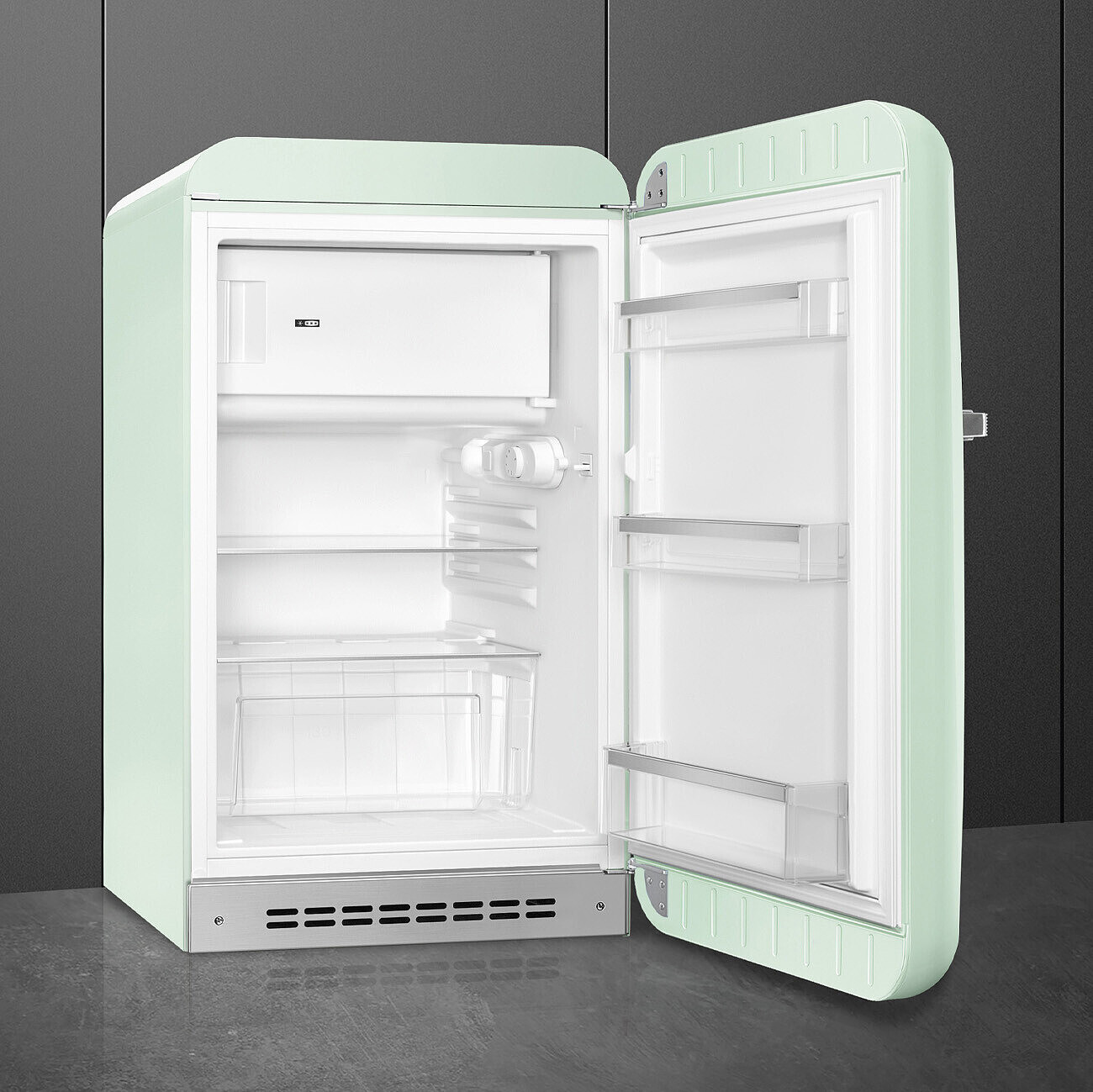 Un frigorifero retrò verde menta con la porta aperta. All'interno, ha ripiani e un vano congelatore. La porta è a destra.