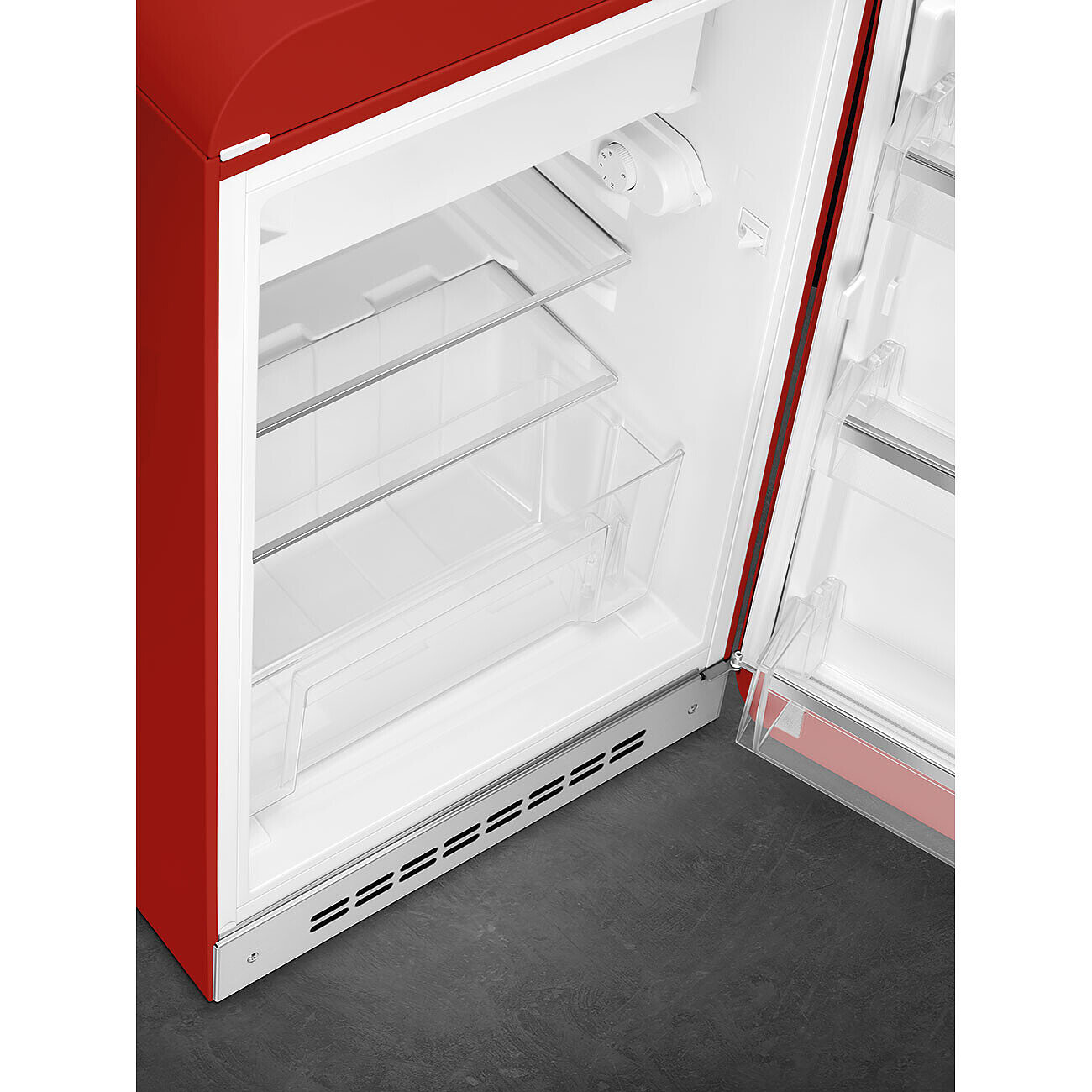 Roter Kühlschrank mit offener Tür. Innen sind transparente Regale und Behälter zu sehen. Die Tür hat einen roten Rahmen. Grauer Boden.