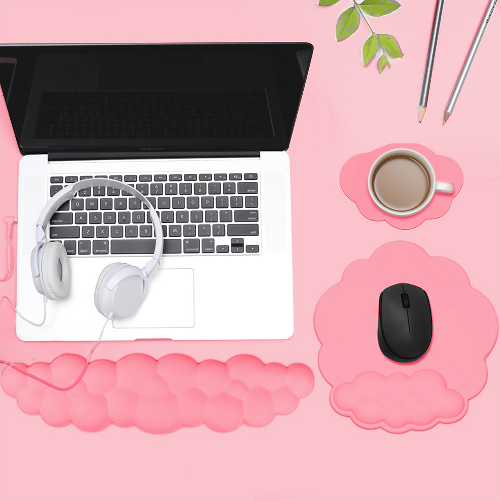 Auf einem rosa Schreibtisch befinden sich ein Laptop, Kopfhörer und eine Maus. Eine Tasse Kaffee und Bleistifte sind ebenfalls sichtbar.