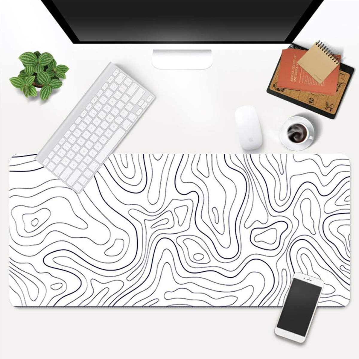 Ein Schreibtisch-Setup mit Computer, Tastatur, Maus, Kaffee, Telefon und einer Mousepad mit topografischem Design.