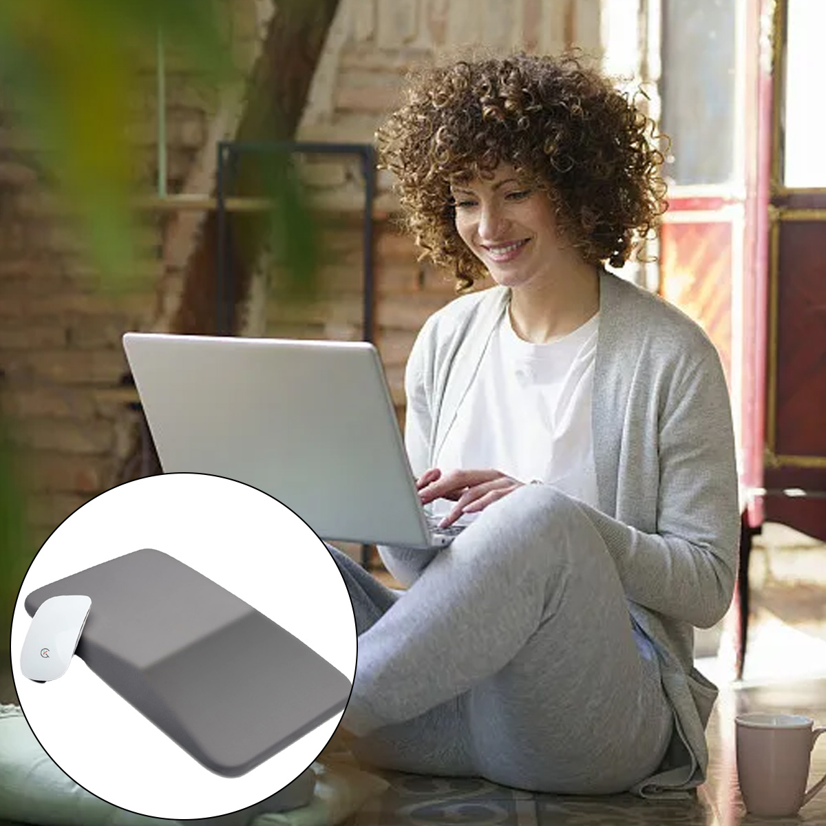 Frau mit lockigem Haar benutzt einen Laptop. Sie sitzt und lächelt. Maus und Pad in einem Kreis.