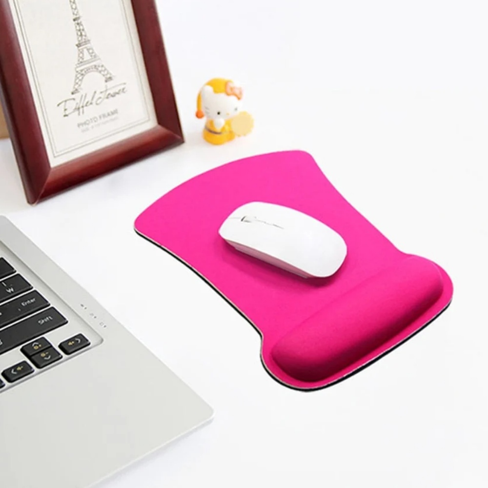Ein pinkfarbenes Mauspadd mit Handgelenkauflage und einer weißen Maus. Dazu ein Laptop und ein kleiner Eiffelturm-Rahmen.