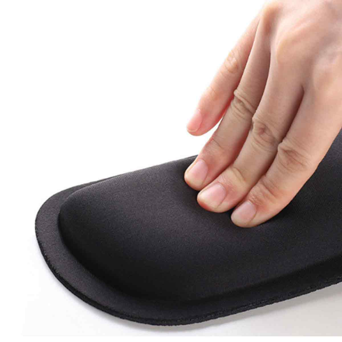 Eine Hand drückt auf eine schwarze, gebogene Handgelenkauflage. Die Auflage hat eine weiche, gepolsterte Oberfläche. Der Hintergrund ist weiß.