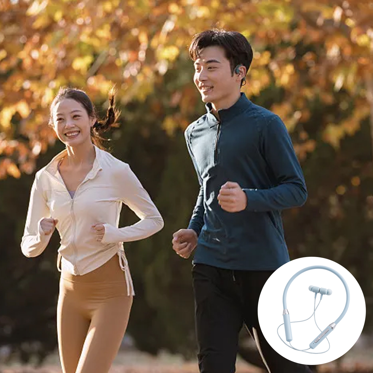 Zwei Personen joggen im Freien und lächeln. Die Frau trägt Beige, der Mann Blau. Herbstlaub im Hintergrund. Enthält ein Headset.