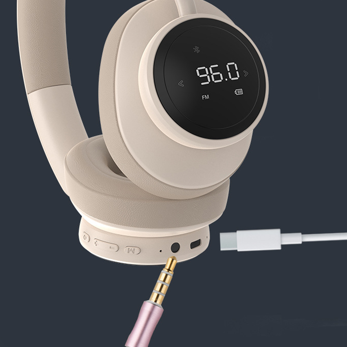 Beige Kopfhörer mit digitaler Anzeige 96.0 FM. Ein goldfarbener Audio-Klinkenstecker ist angeschlossen. Ein USB-C-Kabel ist ebenfalls angeschlossen.