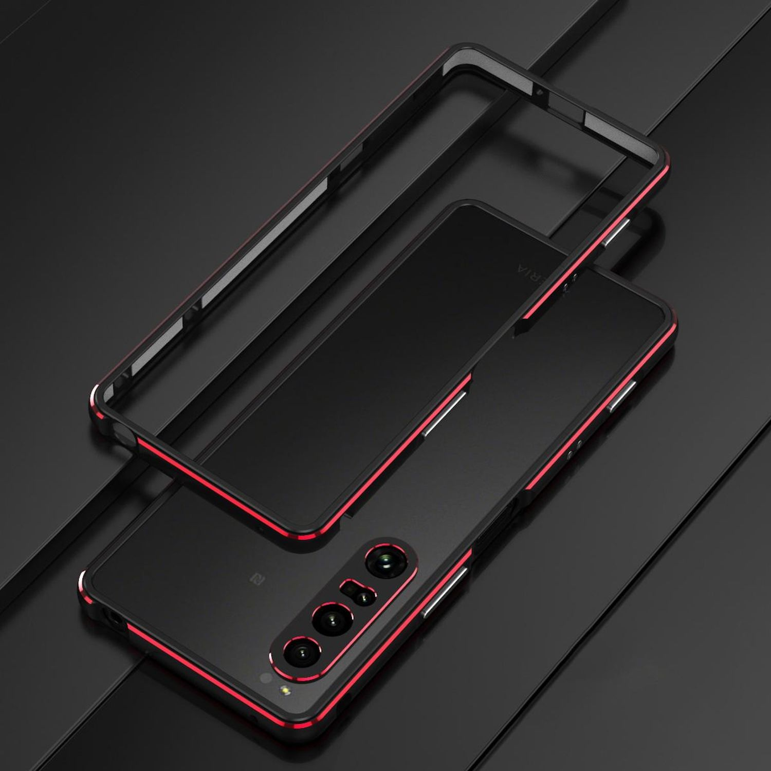 Teléfono negro con detalles en rojo y un marco separado sobre una superficie oscura. El teléfono tiene un conjunto de cámaras y el marco está encima.