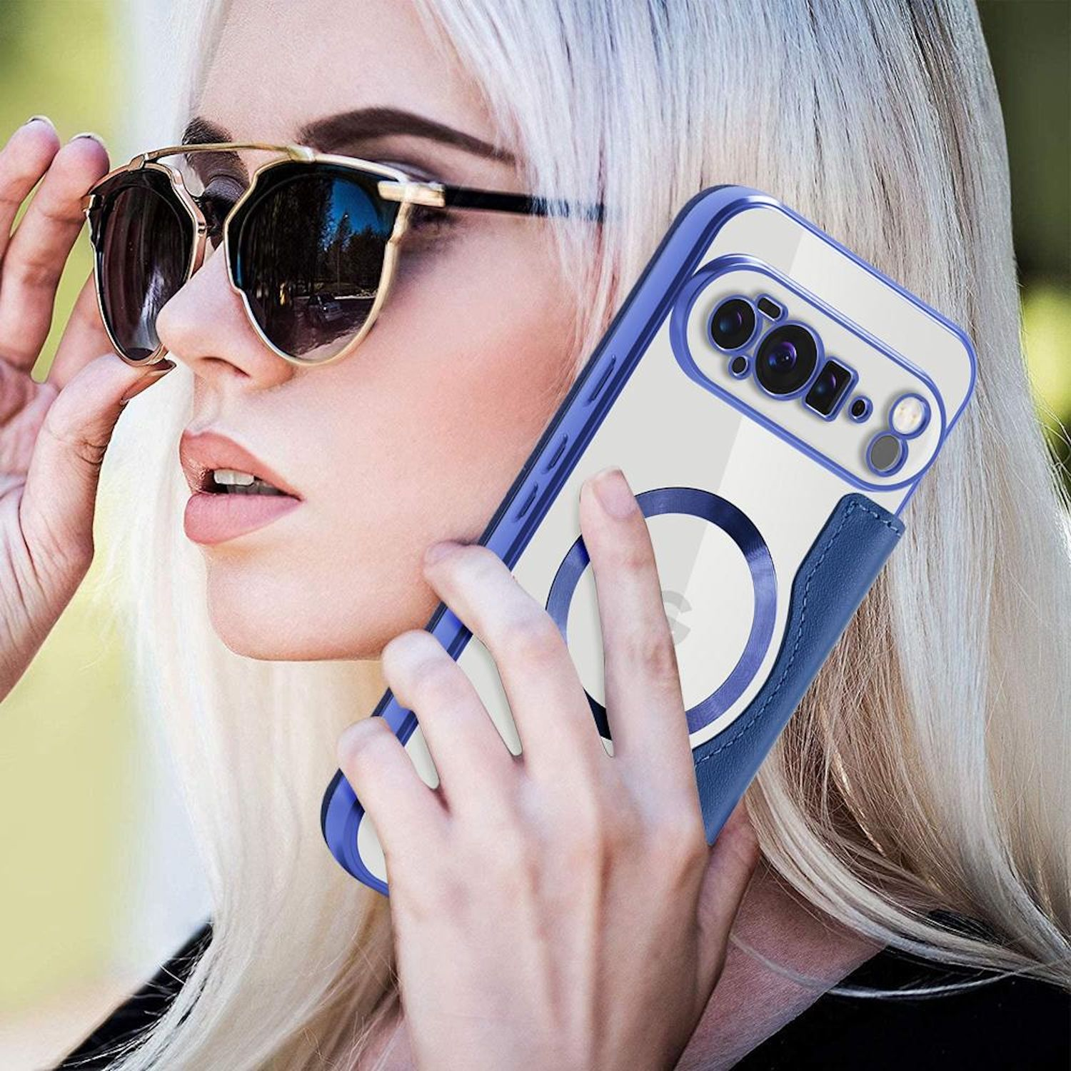 Blonde Frau mit Sonnenbrille hält ein Telefon. Das Telefon hat eine blaue Hülle und einen weißen Kreis. Sie ist draußen.