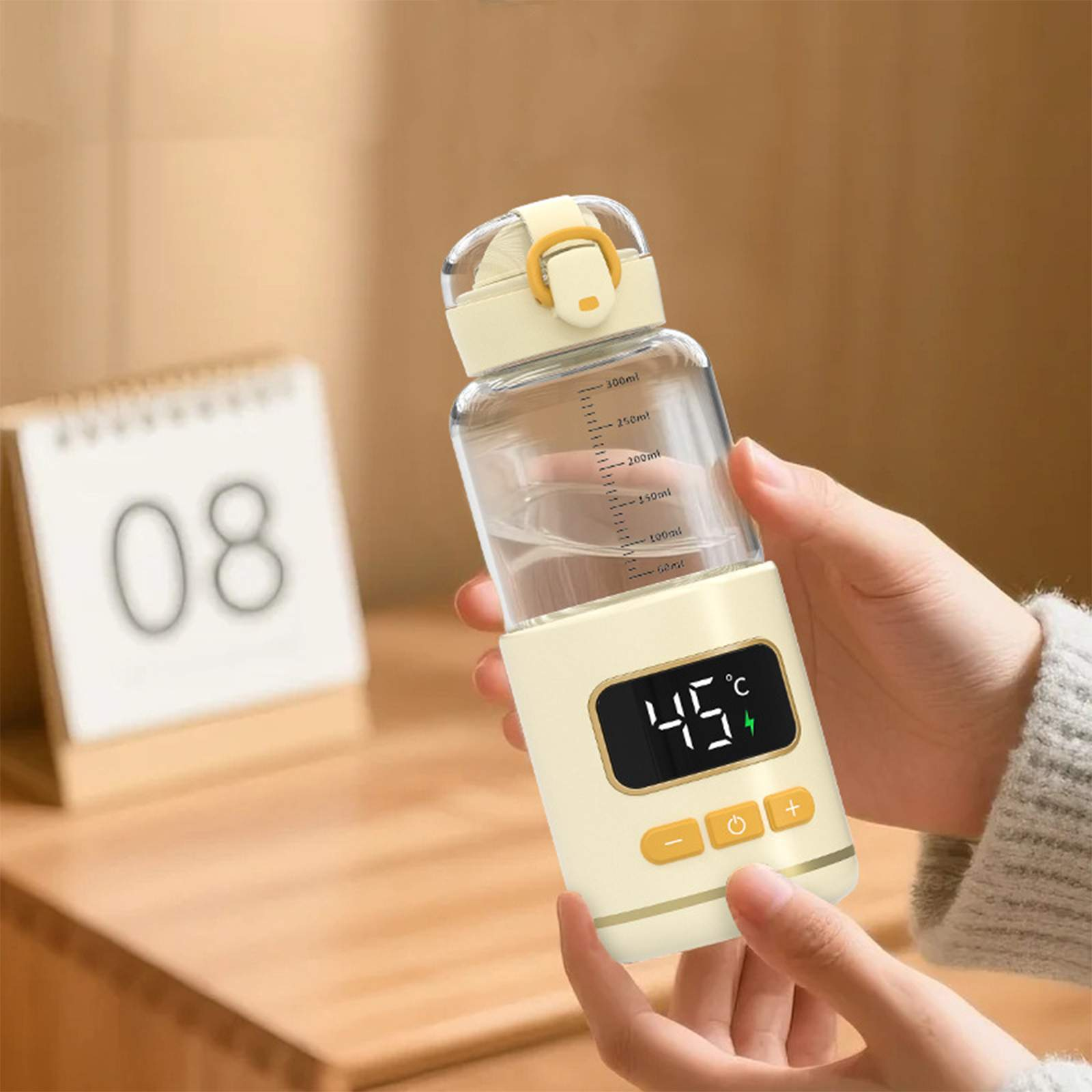Person hält eine cremefarbene Wasserflasche mit 45°C. Ein Kalender zeigt die Zahl 08.