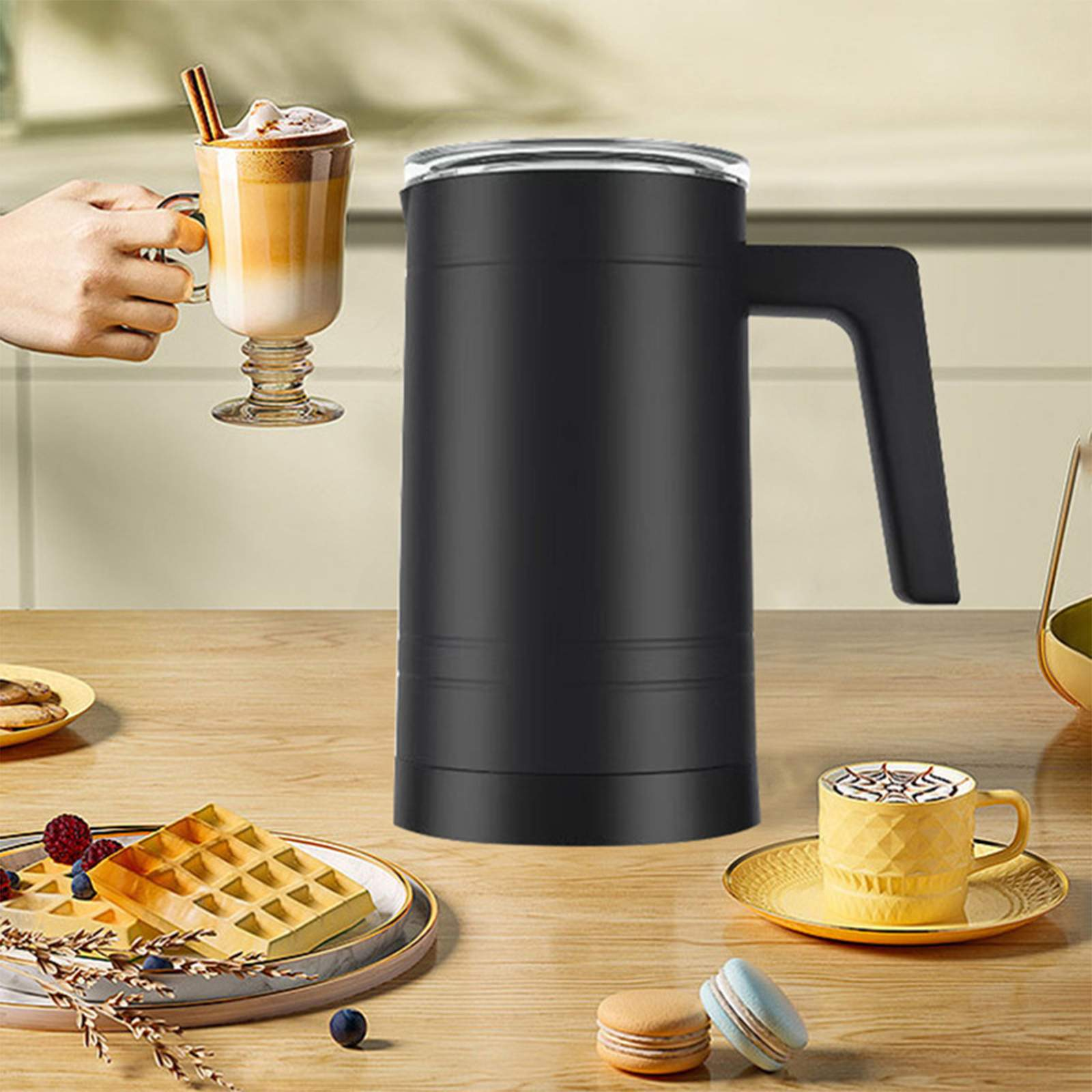 Auf einem Holztisch stehen eine schwarze Kaffeemaschine, ein Latte Macchiato, Waffeln mit Beeren und anderes Gebäck.
