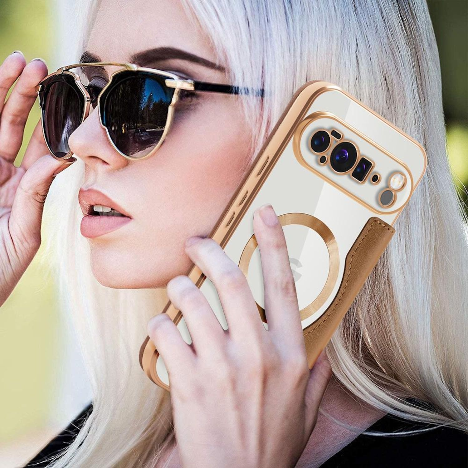 Blonde Frau mit Sonnenbrille, hält ein Telefon in einer goldenen Hülle. Das Telefon hat ein braunes Lederetui.