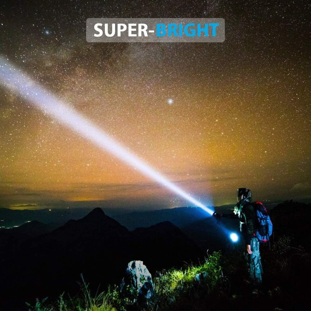 Eine Person auf einem Berg benutzt eine helle Taschenlampe, die den Nachthimmel mit Sternen beleuchtet. Der Strahl zeigt nach oben.