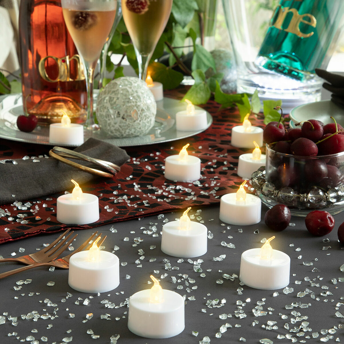 Una mesa festiva con velas, cerezas, champán y elementos decorativos. La escena sugiere una celebración u ocasión especial.