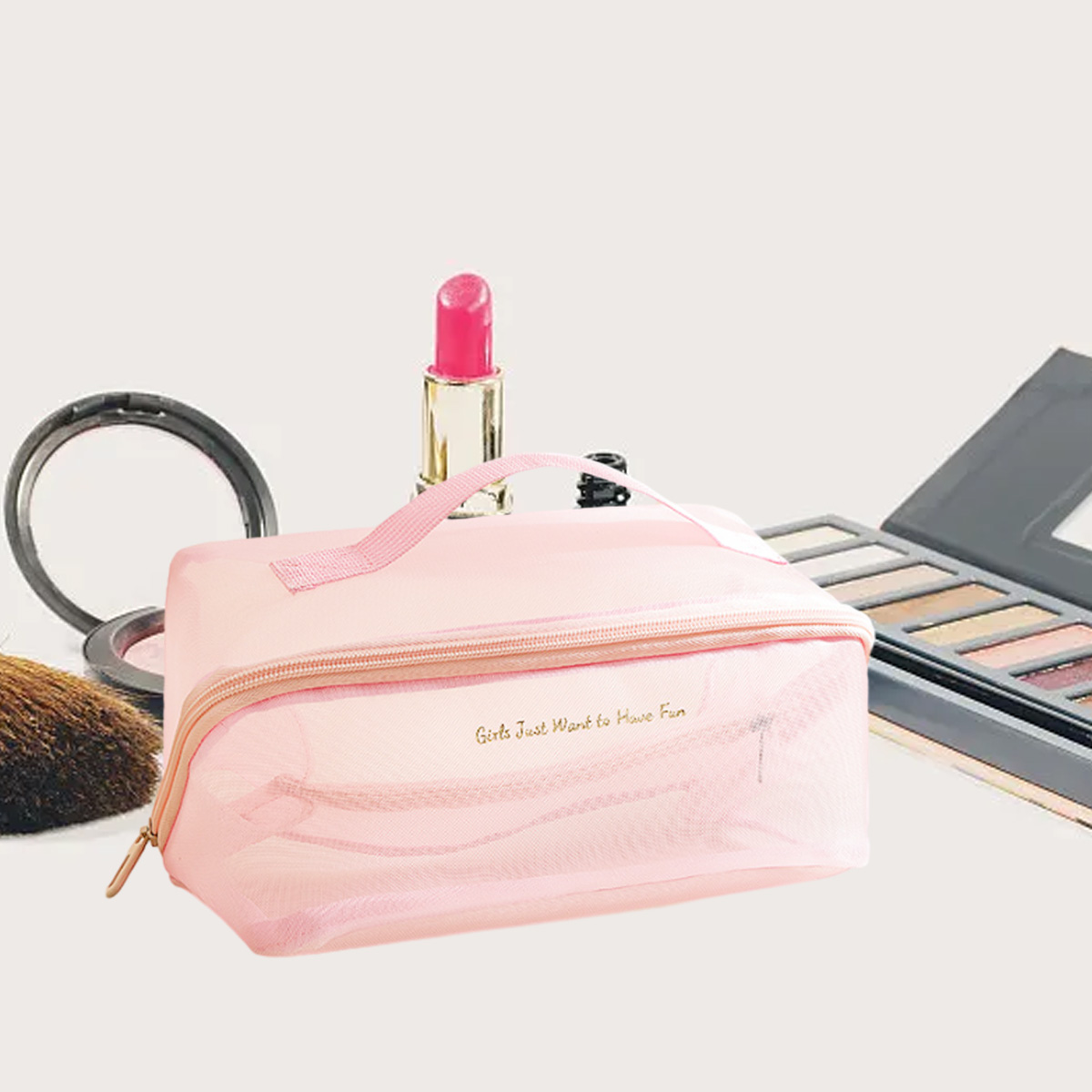 Eine rosa Make-up-Tasche mit dem Text "Girls Just Want to Have Fun" liegt mit Lippenstift, Lidschatten, einem Pinsel und einem Compact.