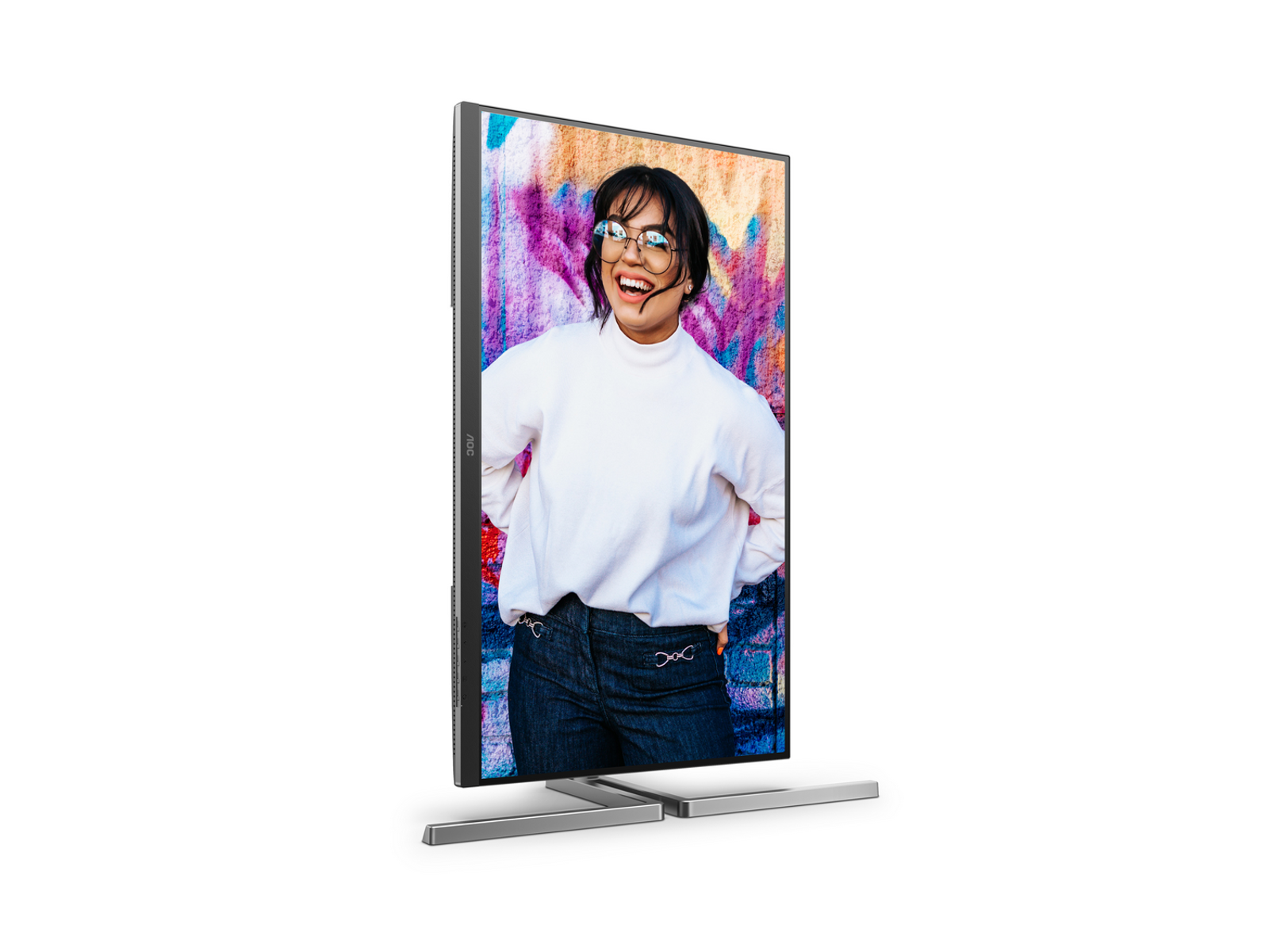 Uśmiechnięta kobieta w okularach jest na monitorze z kolorowym tłem graffiti. Ma na sobie biały sweter i dżinsy.