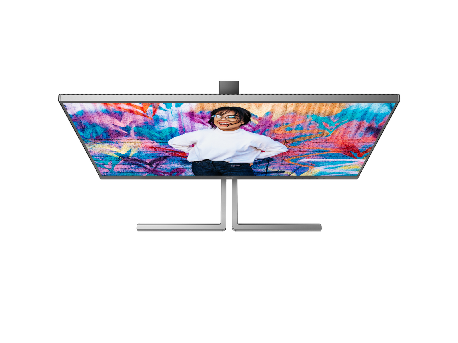 Monitor wyświetla osobę uśmiechającą się przed ścianą graffiti. Monitor ma srebrną ramkę i podstawkę. Tło jest białe.