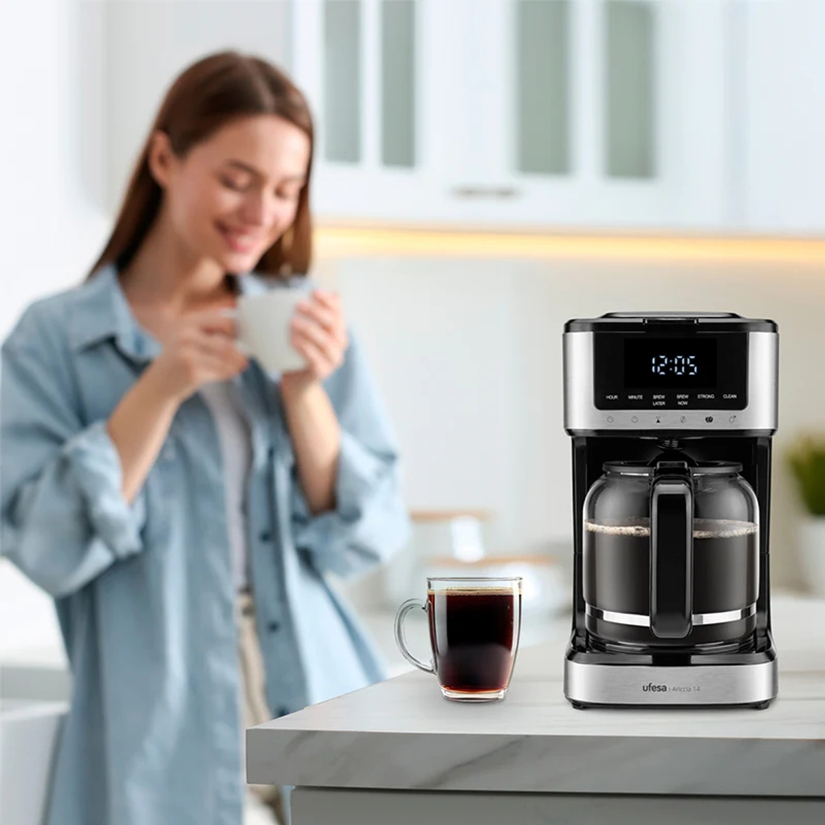 Donna che beve caffè. Macchina da caffè e tazza sul bancone. Sfondo della cucina.
