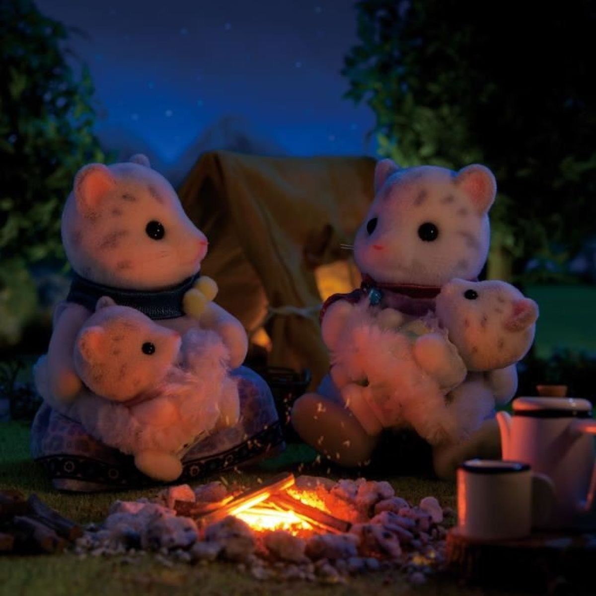 Dos figuras de animales de juguete con bebés sentados alrededor de una fogata. Una tienda de campaña y árboles están en el fondo por la noche. Hay una tetera y tazas.