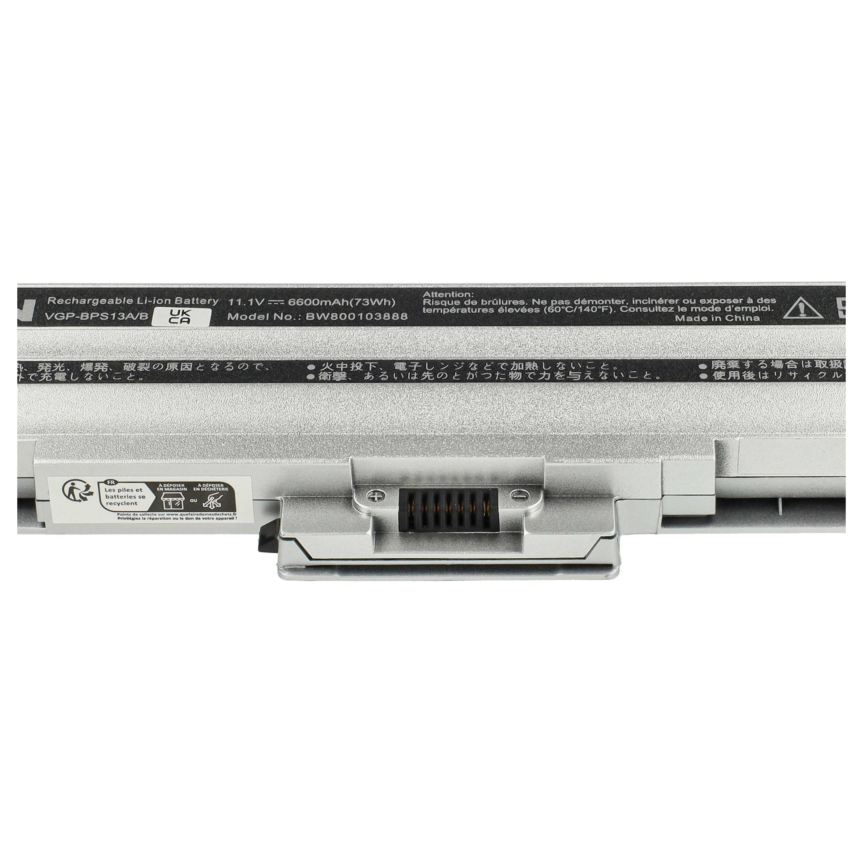 Laptop-Akku mit Text und Warnungen. Silbernes Gehäuse, schwarzer Stecker, Etiketten mit Sicherheitshinweisen.