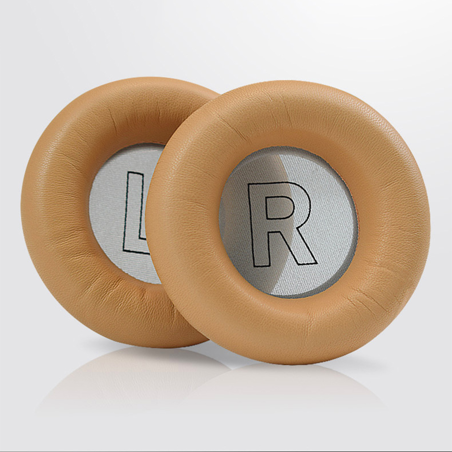 Dwie oprawki słuchawek w kolorze brązowym, jedna z napisem 'L', druga z 'R', na białym tle. Oprawki są okrągłe.