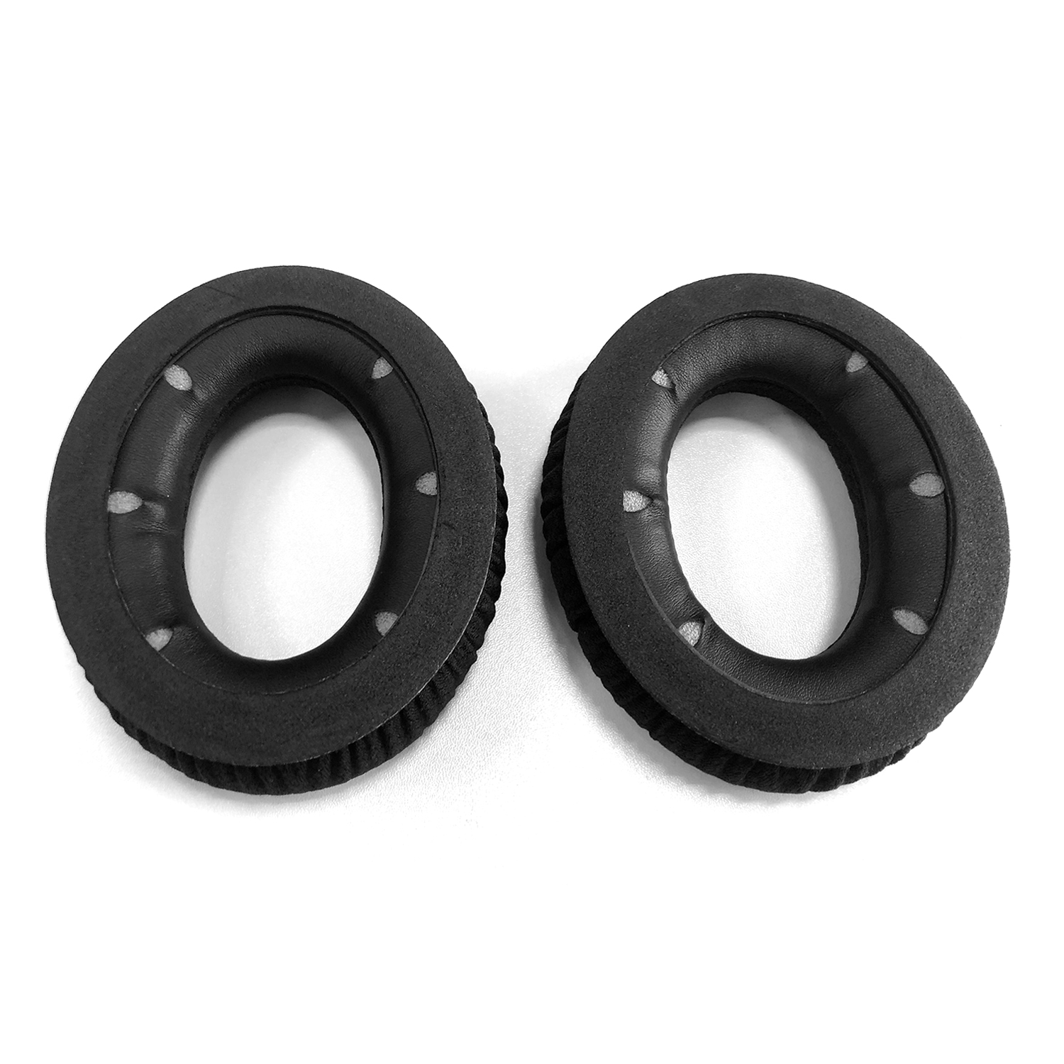 Dwie czarne poduszki na uszy do słuchawek z owalnymi otworami i małymi otworami na krawędziach, na białym tle.