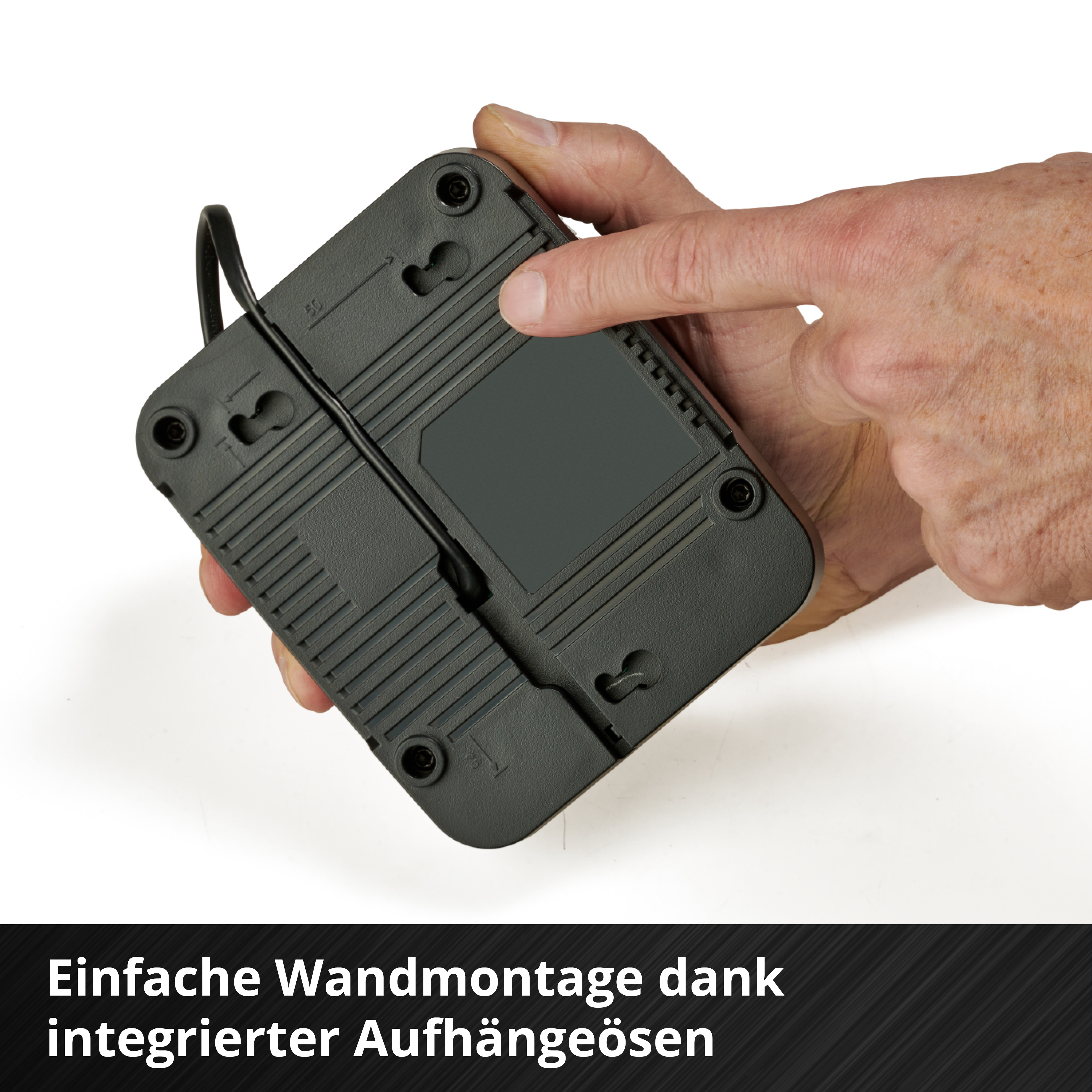 Eine Hand hält ein schwarzes Gerät. Das Gerät hat ein Kabel und befindet sich vor einem weißen Hintergrund. Text unten.