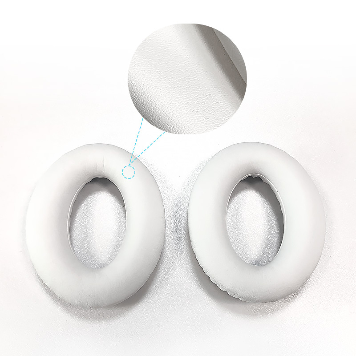 Dwie białe, owalne wkładki douszne z powiększonym detalem pokazującym teksturowaną powierzchnię. Tło jest białe.
