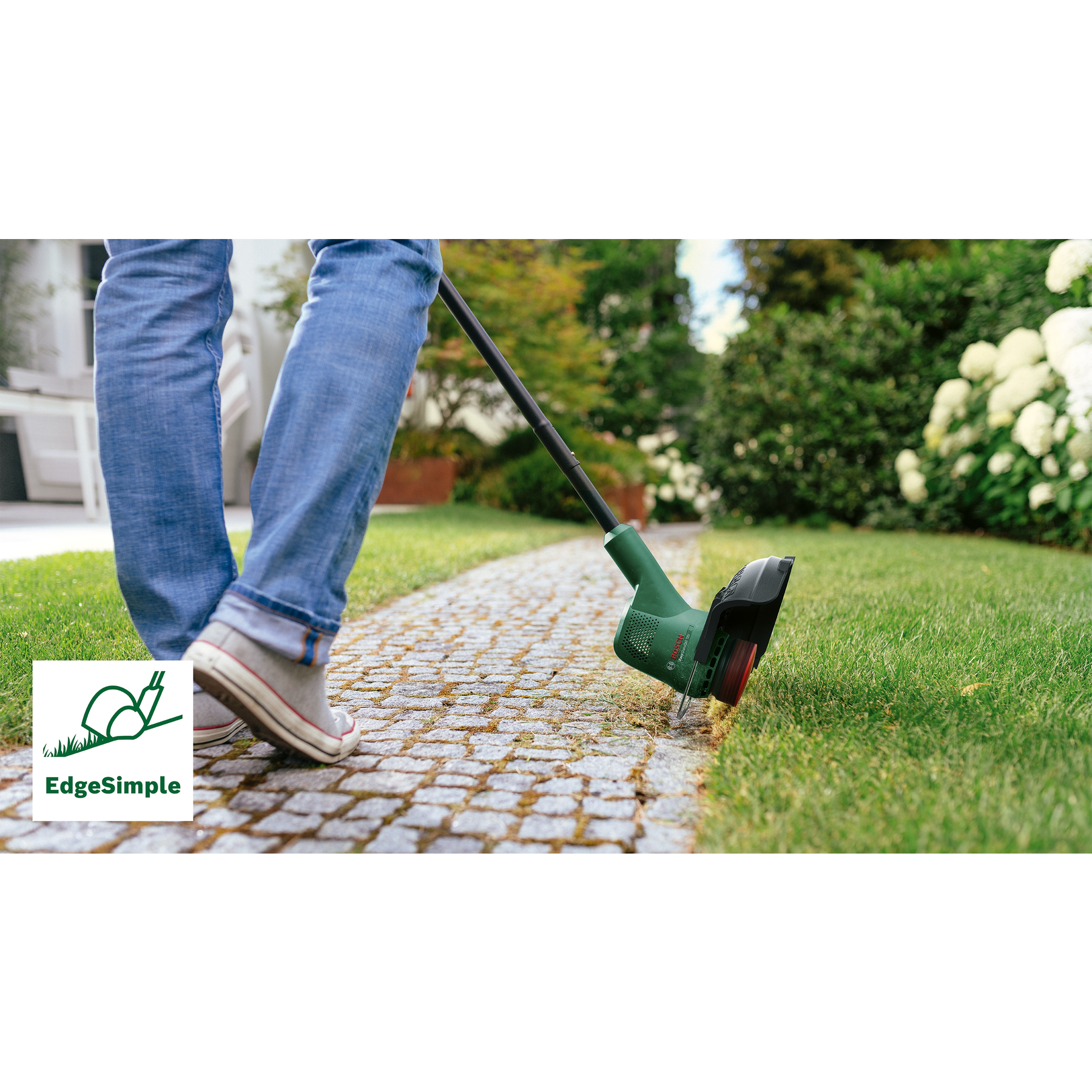 Eine Person schneidet Rasenkanten mit einem grün-schwarzen Trimmer. Die Szene umfasst einen gepflasterten Weg und grünes Gras.