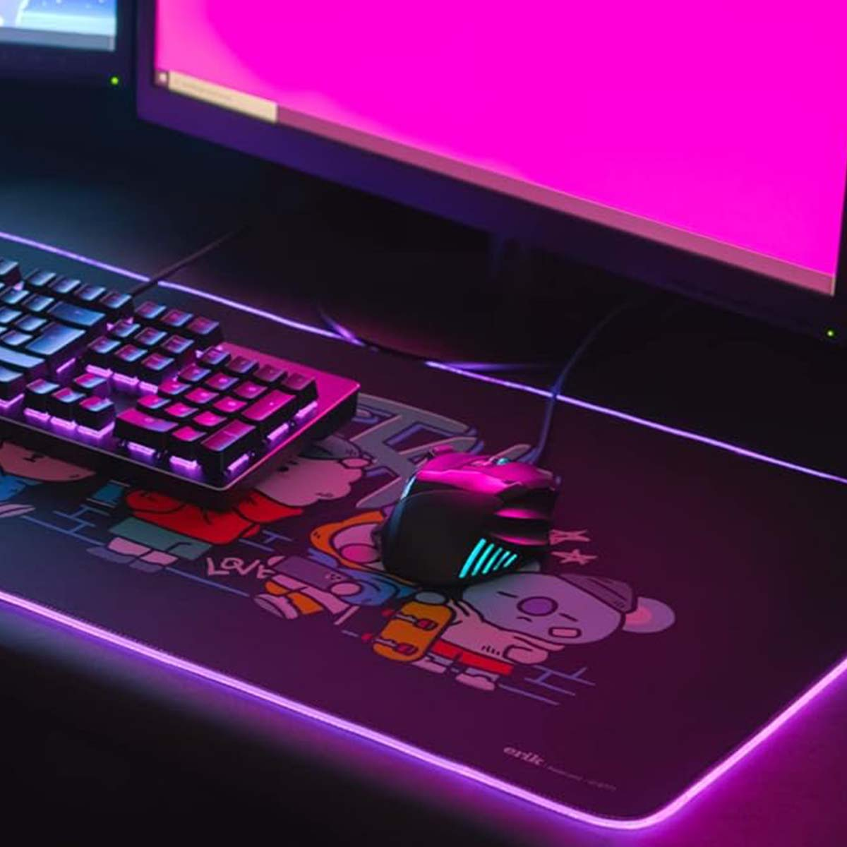 Ein Gaming-Setup mit Tastatur, Maus und Mauspad mit Cartoon-Design. Der Bildschirm ist hellrosa.