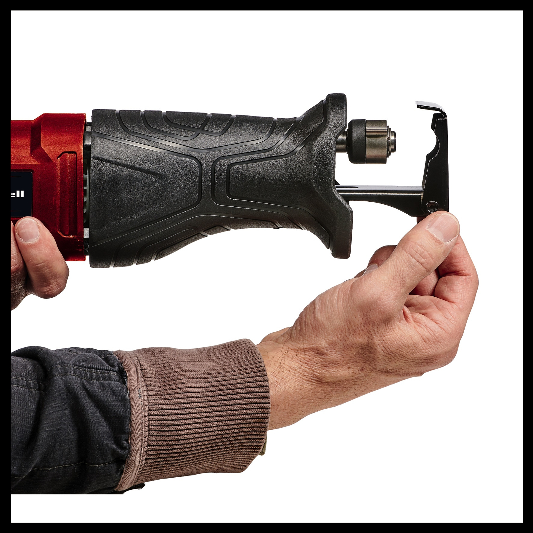 Osoba trzyma czerwono-czarną piłę posuwisto-zwrotną. Piła trzymana jest w dwóch rękach na białym tle.