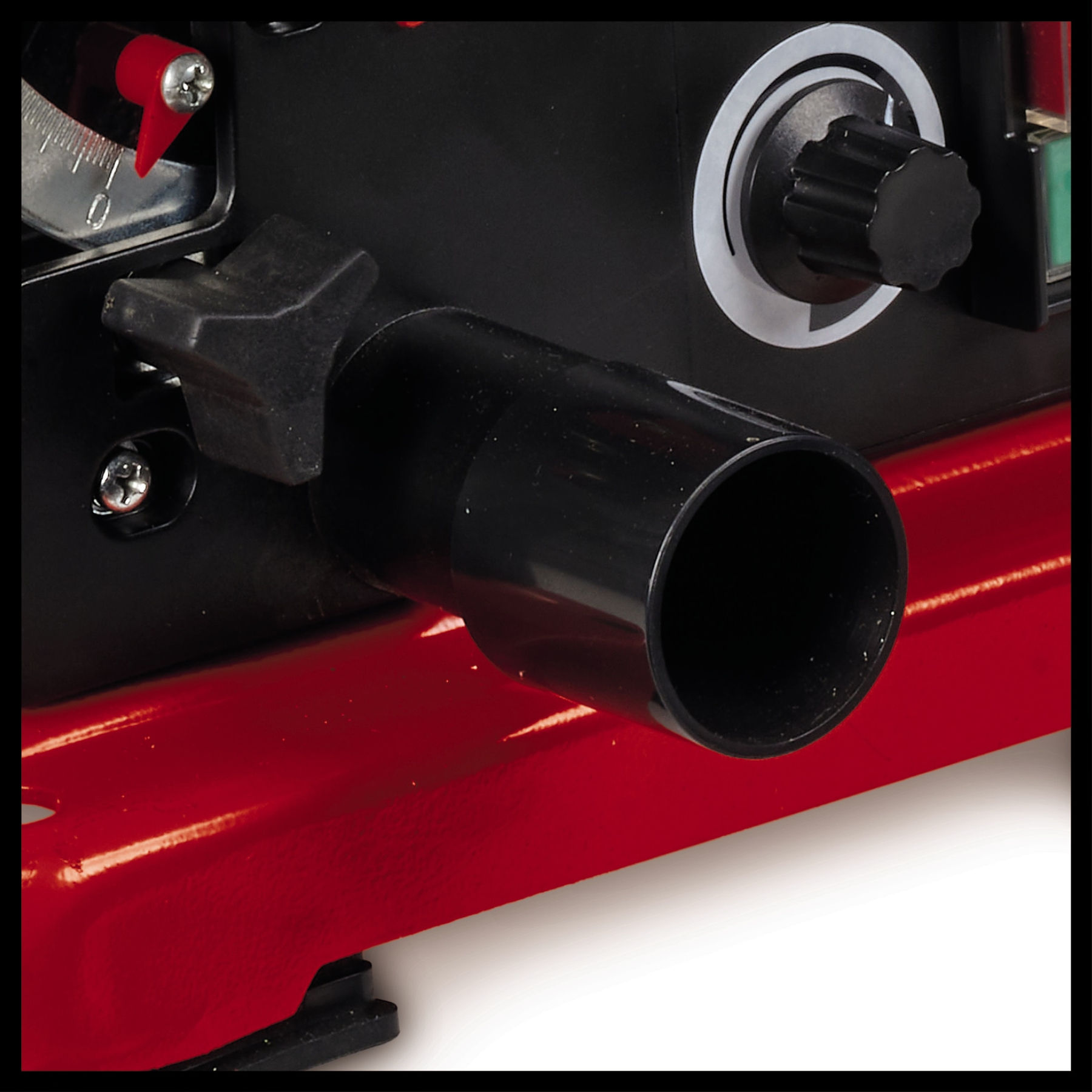 Zbliżenie czarnego elementu maszyny z okrągłym otworem, pokrętłem oraz czerwonymi i czarnymi powierzchniami, prawdopodobnie sprzęt przemysłowy.