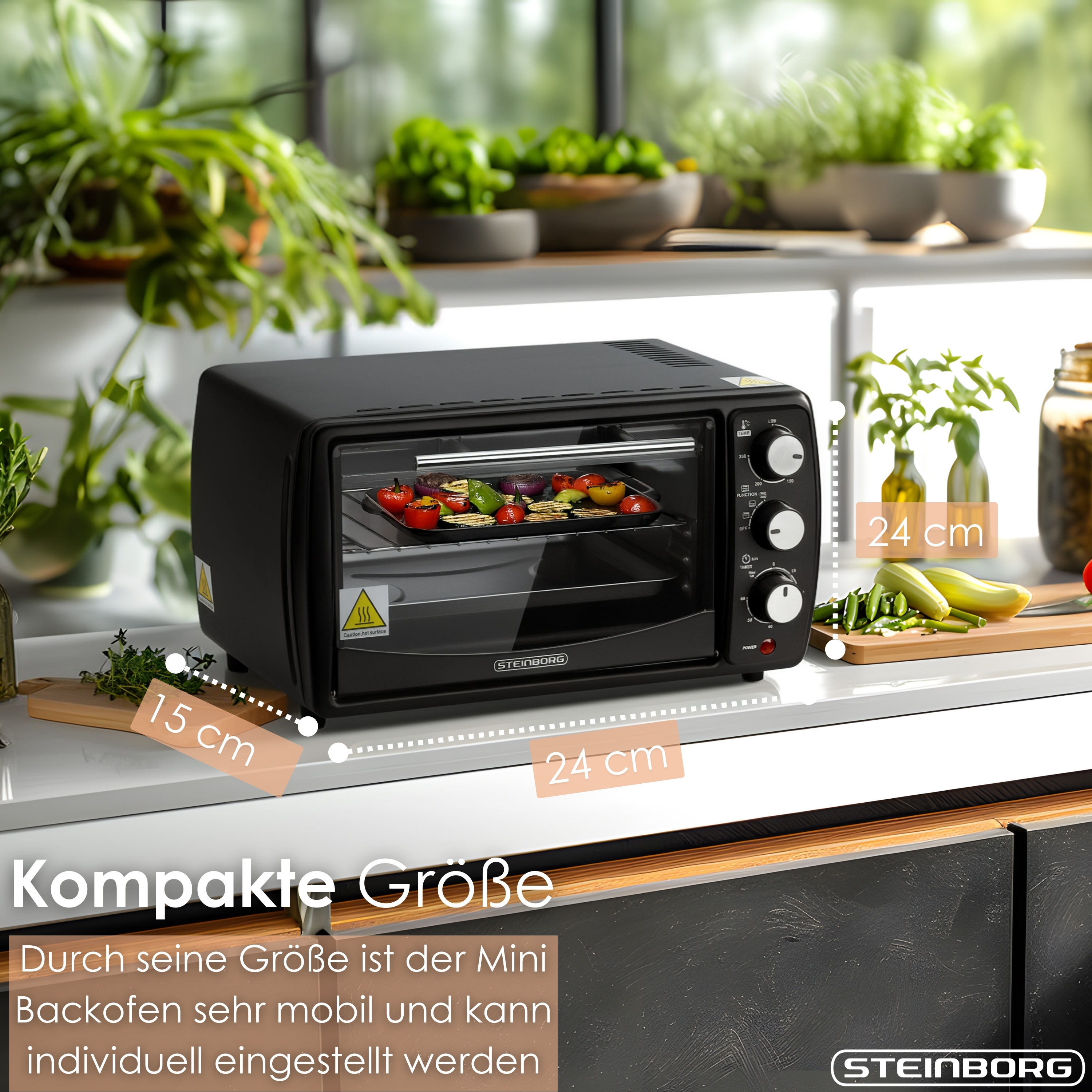 Ein schwarzer Mini-Backofen mit Gemüse. Küchentheke mit Pflanzen im Hintergrund. Abmessungen sind angegeben.