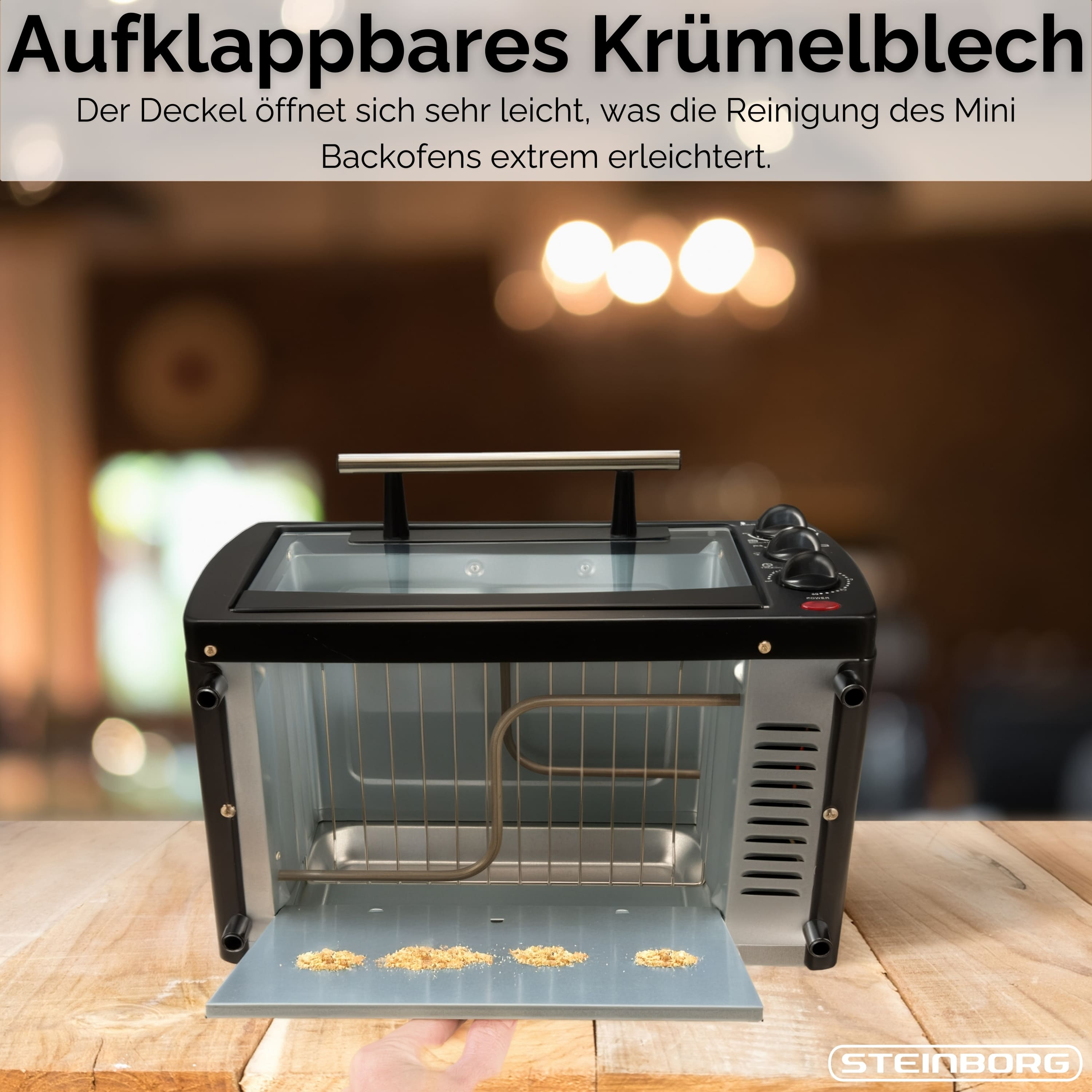 Ein Mini-Ofen mit offenem Krümelblech. Das Krümelblech hat Krümel. Der Hintergrund ist verschwommen.