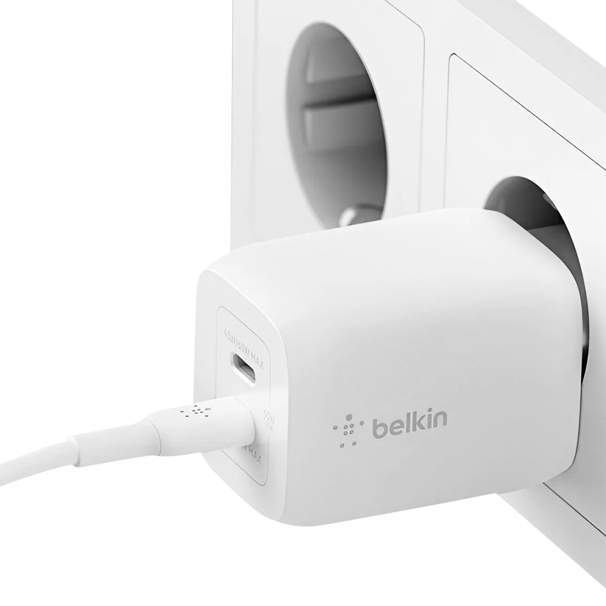 Un caricabatterie Belkin bianco è collegato a una presa a muro. Un cavo bianco si collega al caricabatterie.