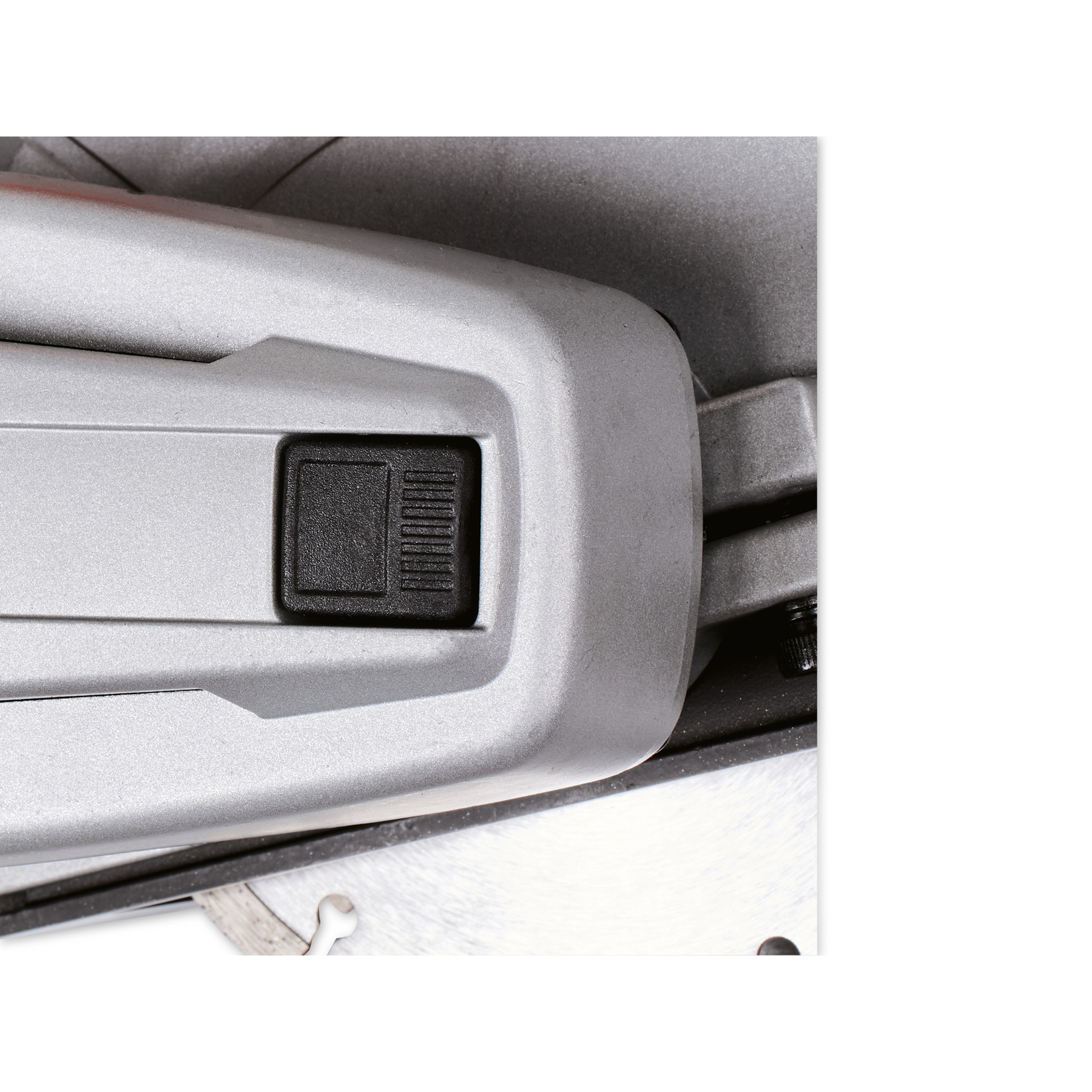 Nahaufnahme eines grauen Elektrowerkzeugs mit schwarzem Knopf. Das Werkzeug hat eine metallische Textur und vor weißem Hintergrund.