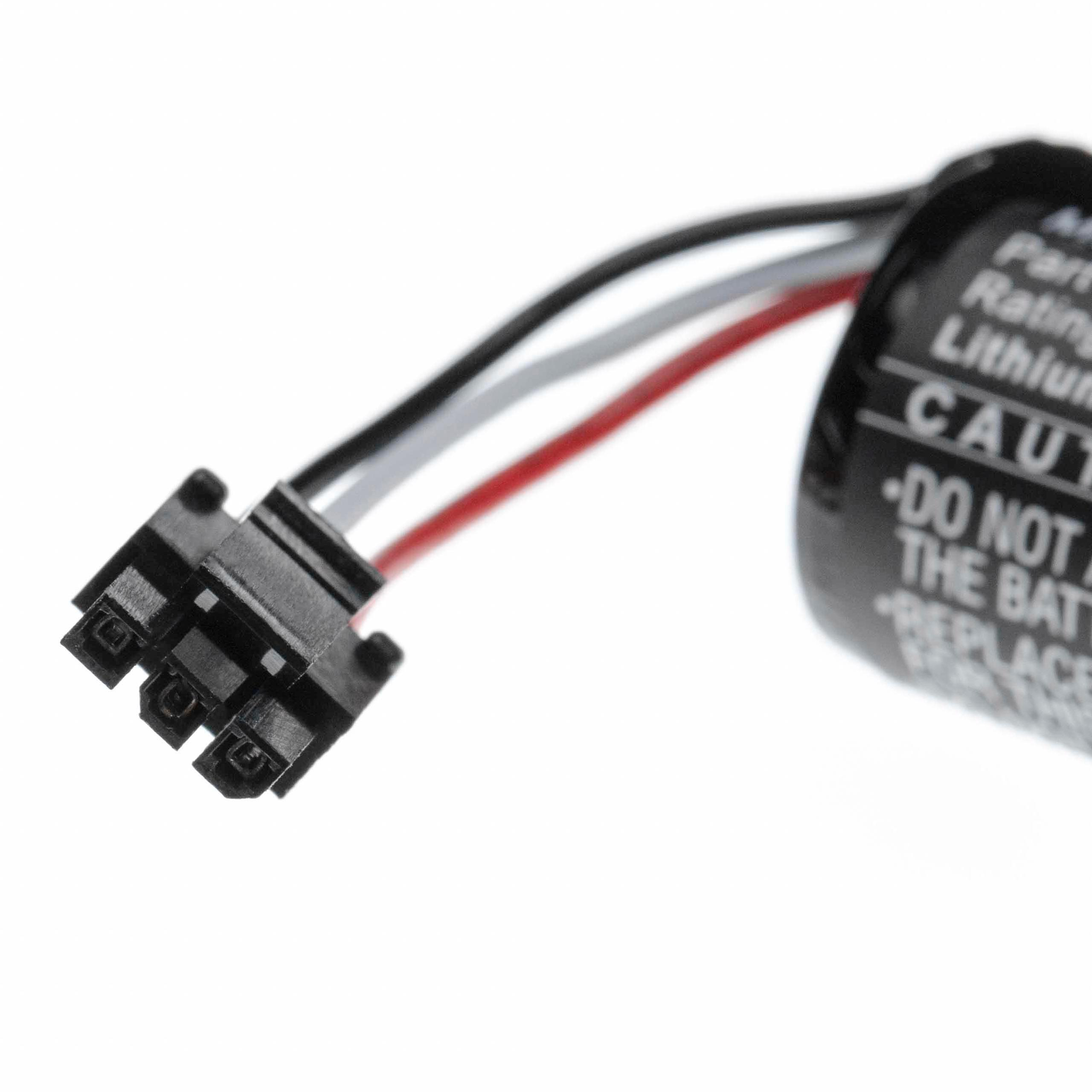 Nahaufnahme eines schwarzen Batteriesteckers mit Drähten neben einer zylindrischen Batterie mit Warnhinweisen. Weißer Hintergrund.
