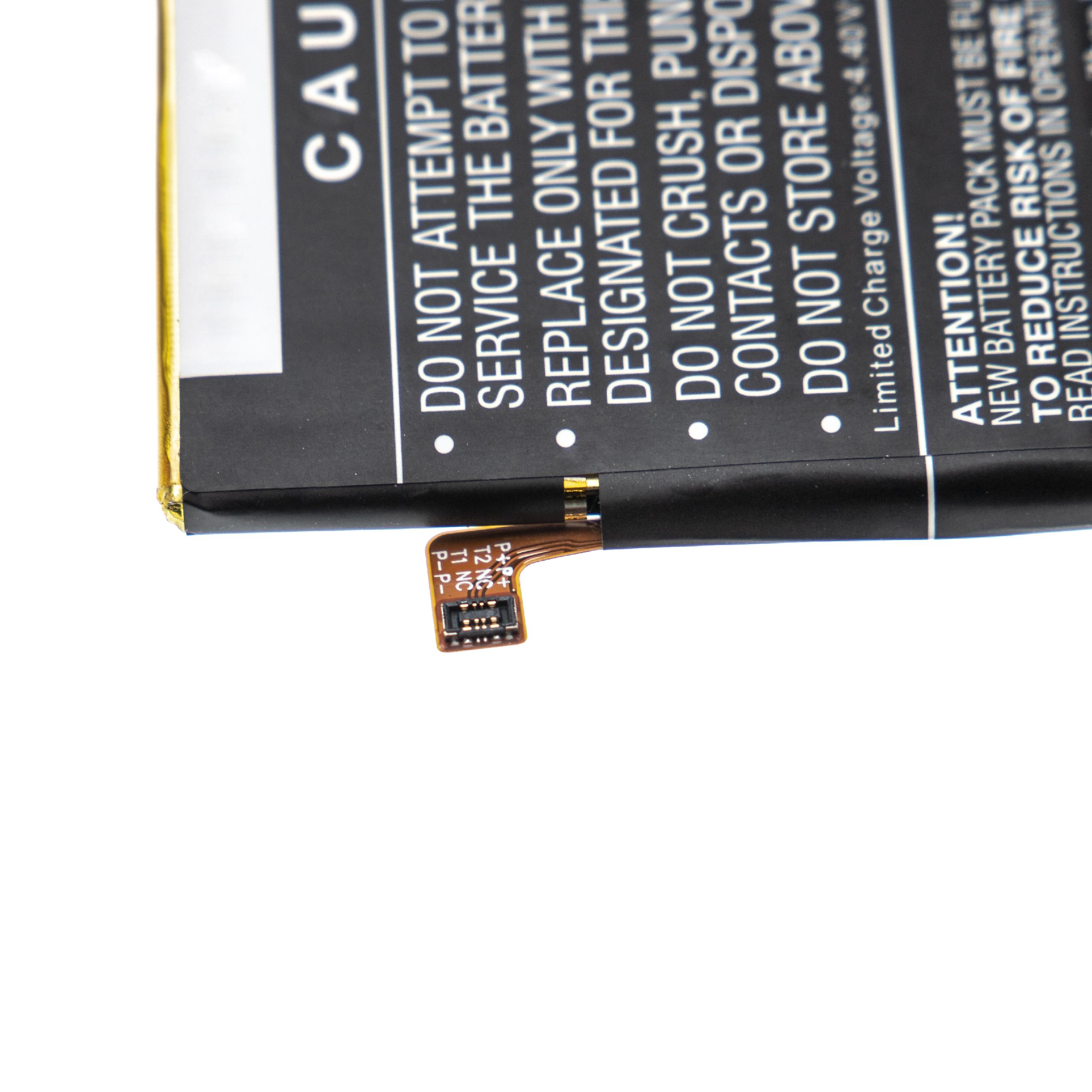 Nahaufnahme eines Akkus mit Warnhinweisen. Schwarz und Weiß mit goldfarbener Kante und kleinem Stecker.