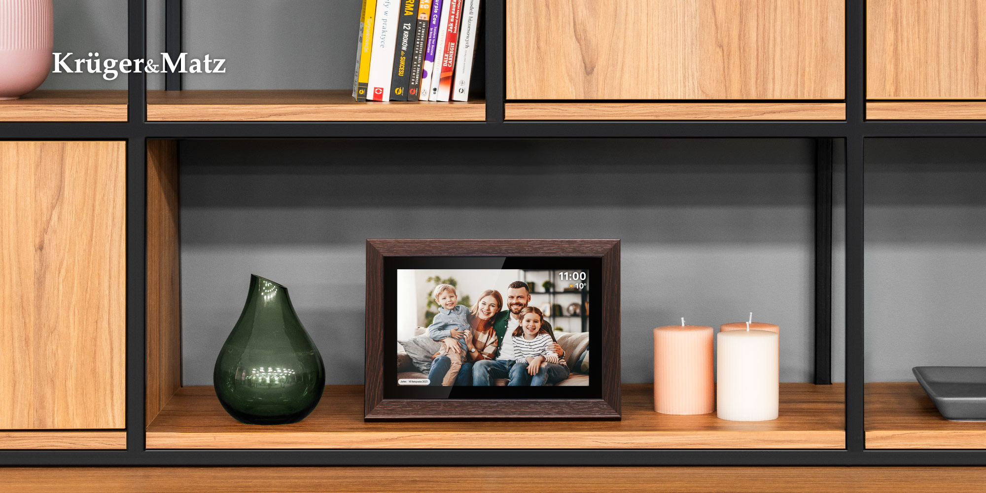 Drewniana półka z ramką na zdjęcia rodzinne, zielonym wazonem i świecami. Książki na górnej półce, tło szare.