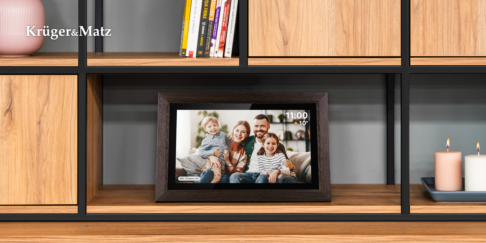 Cyfrowa ramka na zdjęcia wyświetla portret rodzinny. Ramka stoi na drewnianej półce, w pobliżu świece i książki.