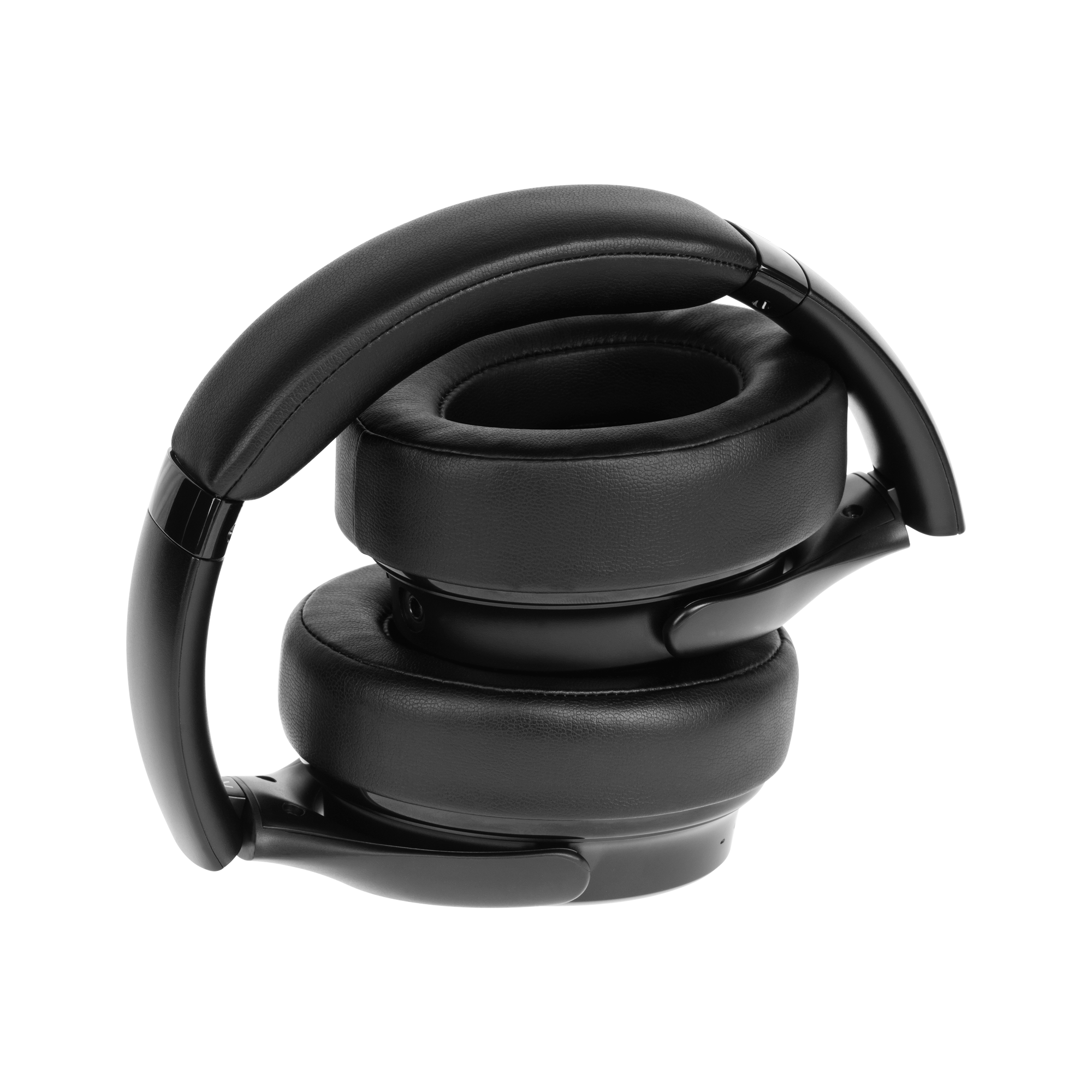 Czarne, złożone słuchawki. Muszle są duże i okrągłe. Pałąk jest wygięty. Tło jest białe.