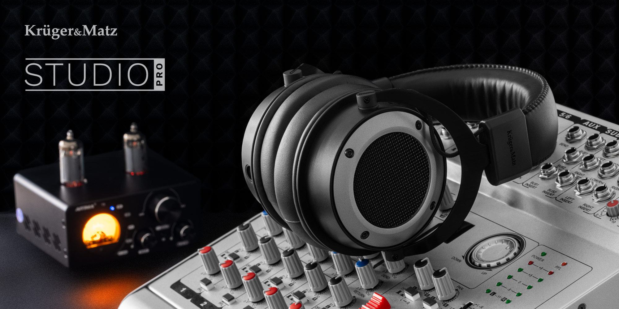 Czarne słuchawki studyjne na konsoli mikserskiej. Czarny wzmacniacz z jarzącymi się lampami w tle.