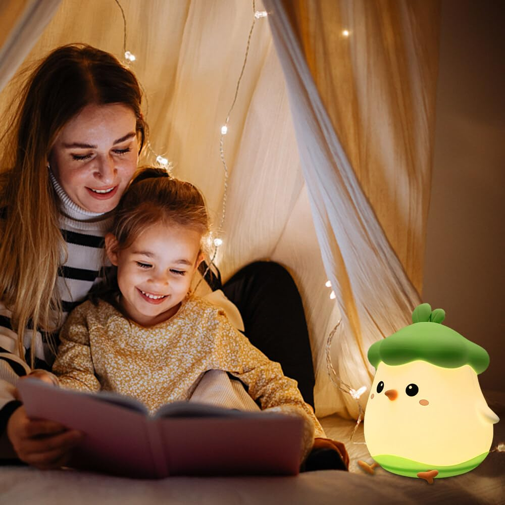Mutter und Tochter lesen in einem Zelt, beleuchtet von Lichterketten und einer kükenförmigen Lampe. Beide lächeln. Das Buch ist offen.