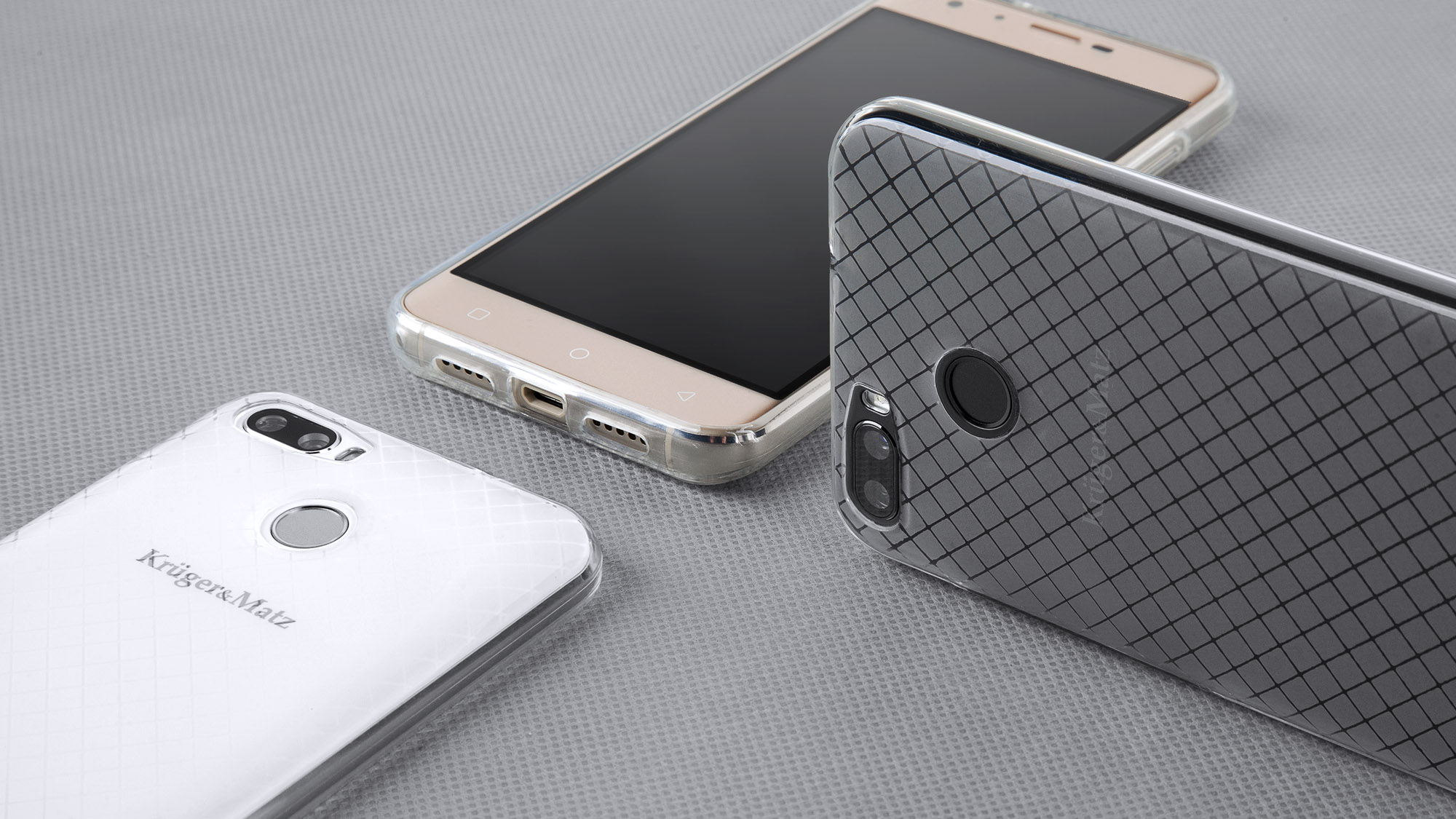 Trzy smartfony z etui ochronnymi na teksturowanej szarej powierzchni. Etui są przezroczyste, białe i szare. Jeden telefon jest różowo-złoty.